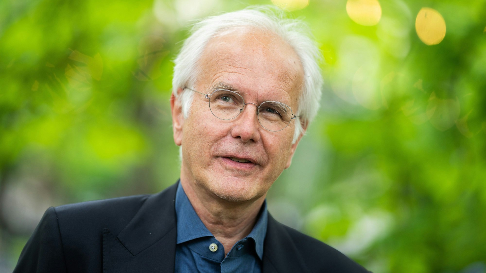 Harald Schmidt, Kabarettist aus Deutschland, anlässlich des Auftakts der neuen Freiluftbühne «Theater im Park». Er steht vor unscharfem grünen Hintergrund und schaut an der Kamera vorbei