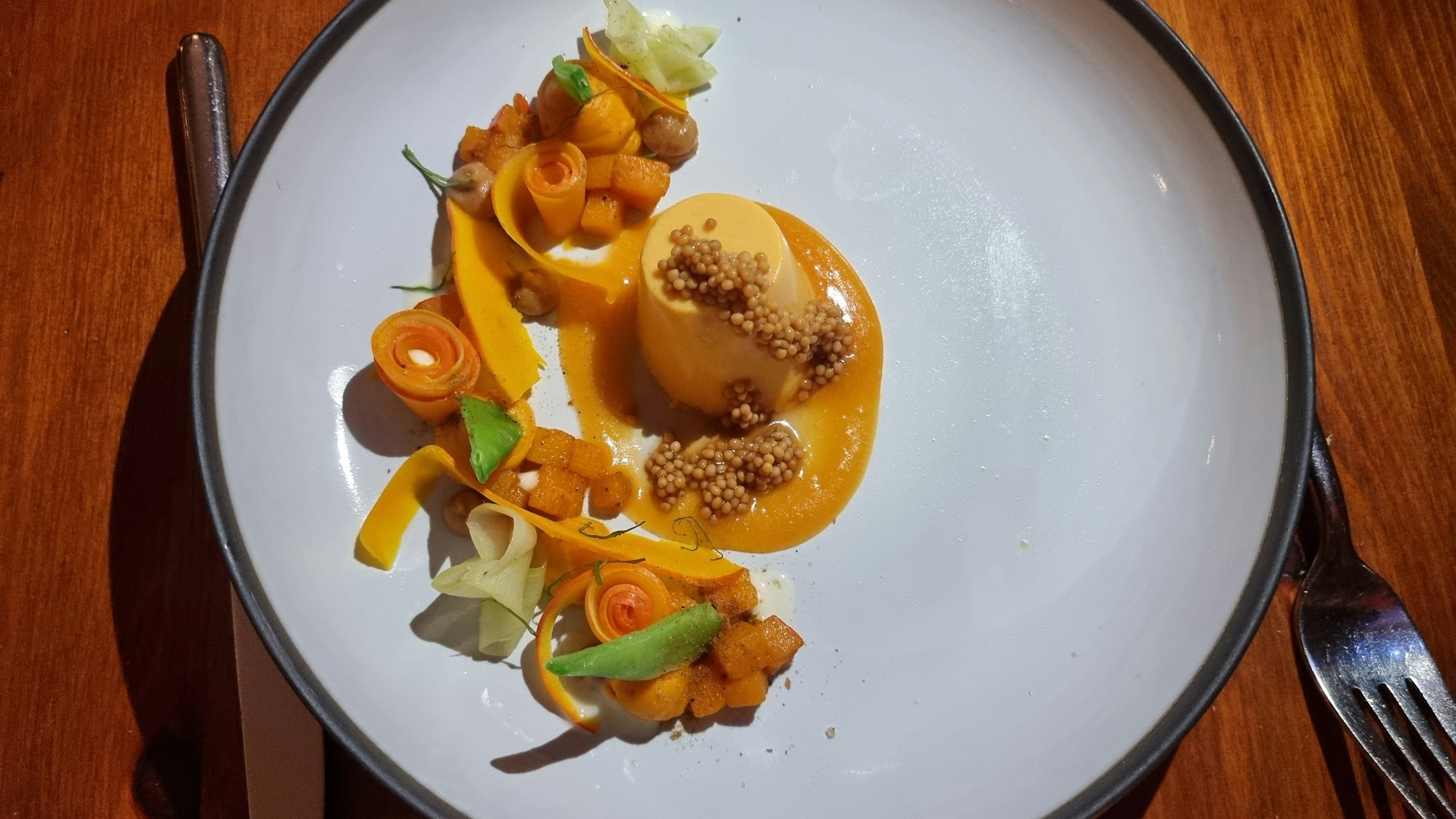 Teller mit Hokkaido-Panna-Cotta mit Passionsfrucht, Zwiebelmilch, Senfkörnern und Crème fraîche.