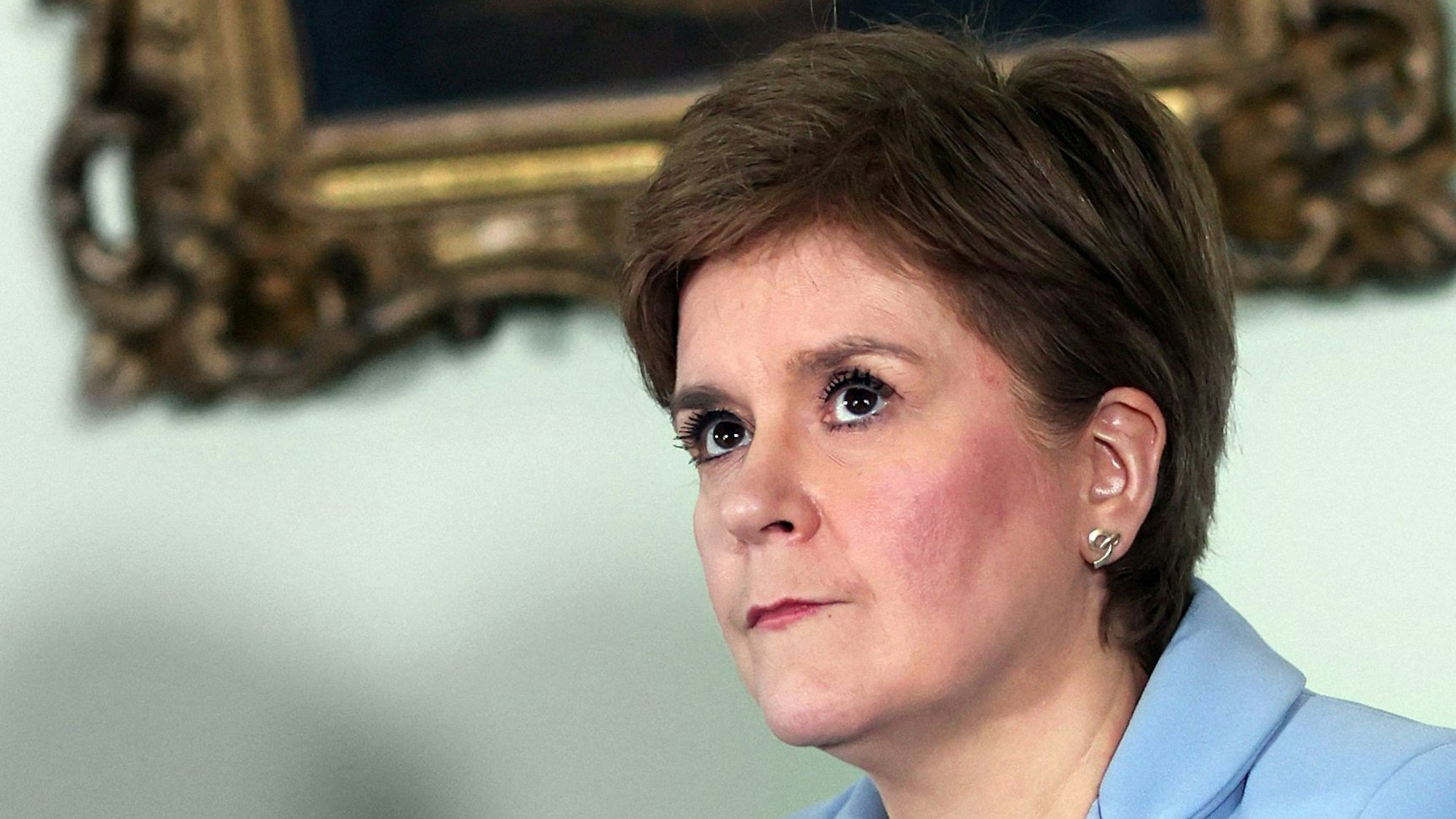 Nicola Sturgeon, Ministerpräsidentin von Schottland steht vor einem goldenen Bilderrahmen und schaut nach oben.