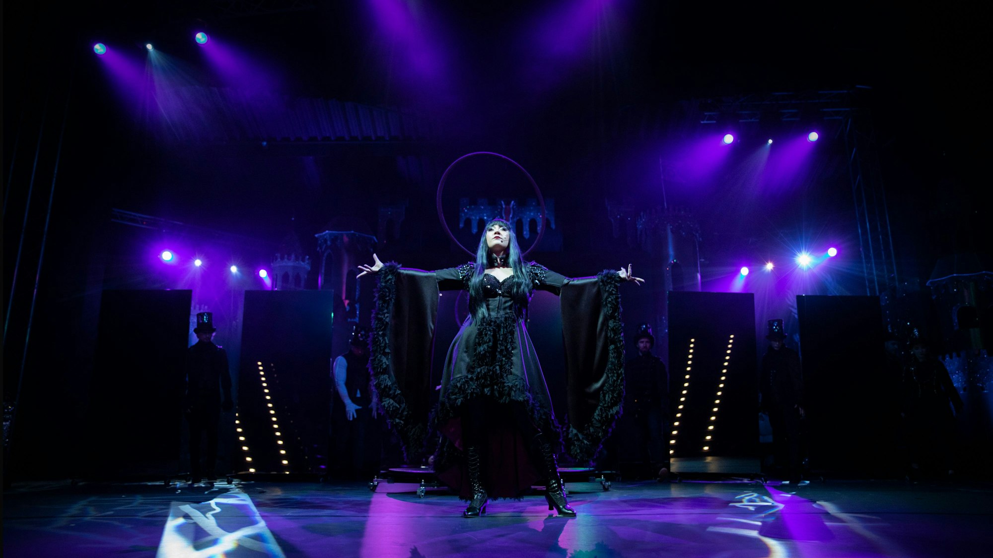 Eine der Bühnendarstellerin steht auf der Bühne, im Hintergrund leuchten die Scheinwerfer.
