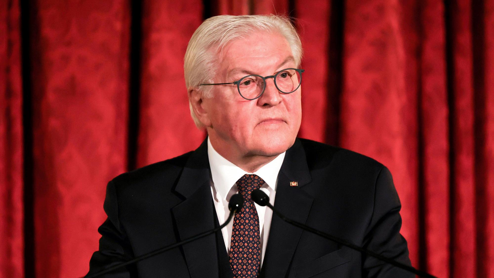 Bundespräsident Frank-Walter Steinmeier spricht nach der Verleihung des Henry-Kissinger-Preises 2022. Er steht vor einem roten Vorhang und guckt ernst an der Kamera vorbei.