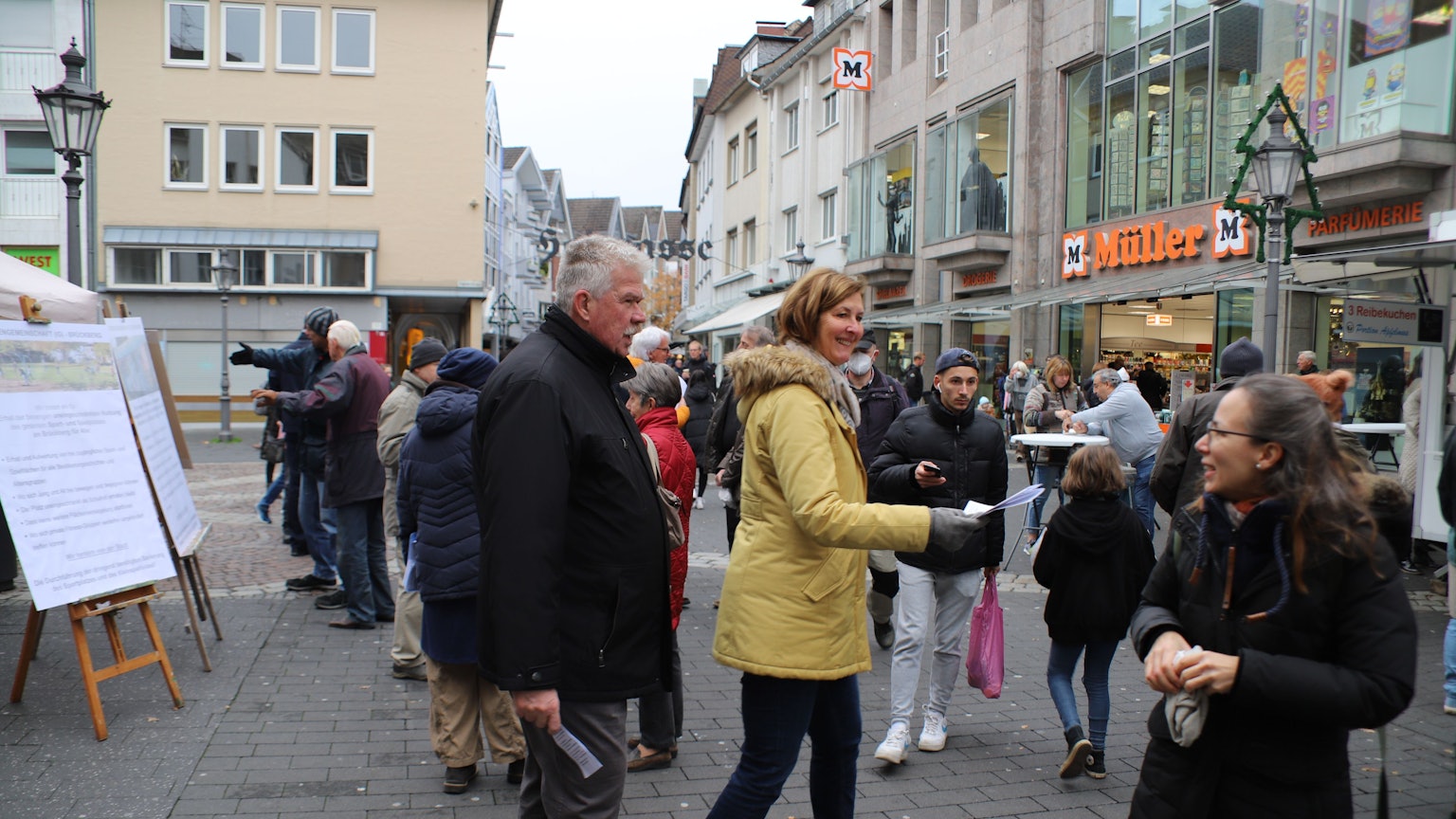 Zwei Bürgerinnen sprechen mit Zetteln in der Hand Passanten an. Sie haben ein Flipchart aufgestellt.