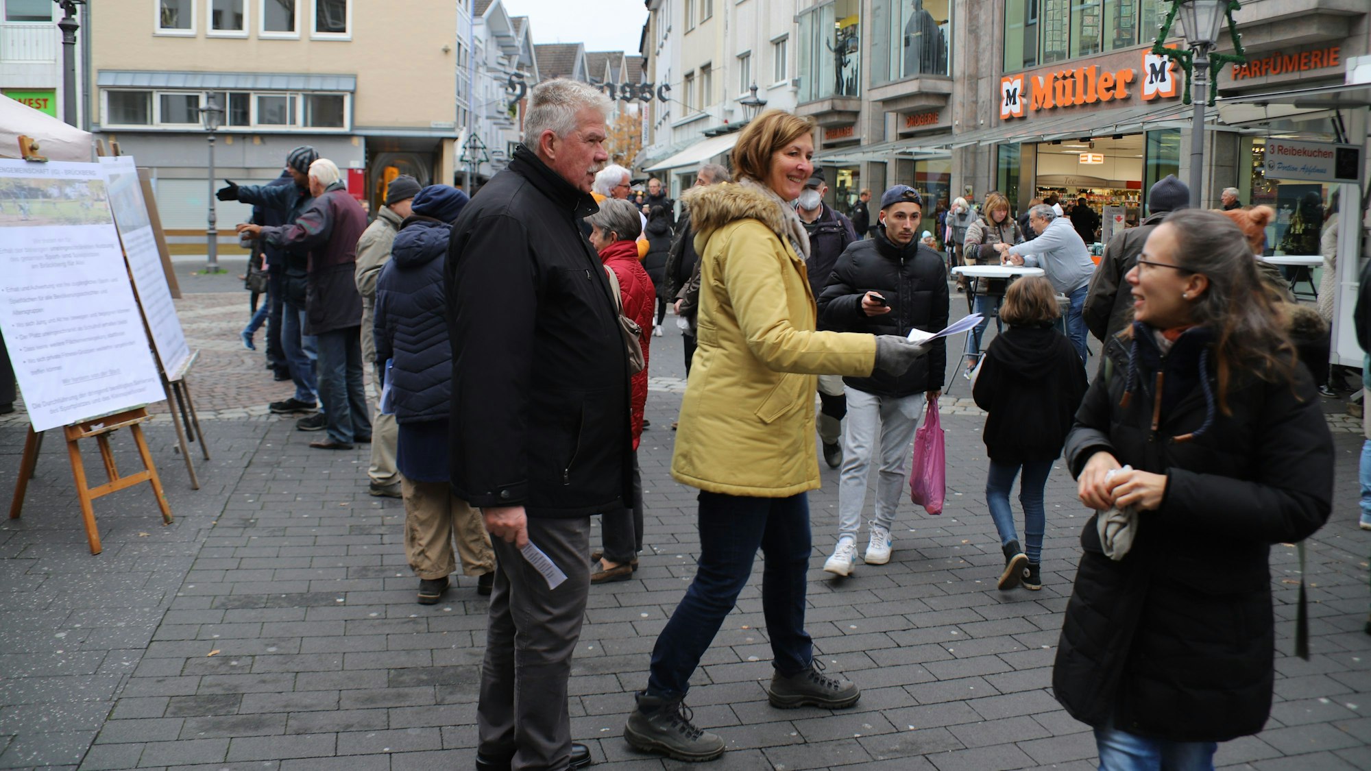 Zwei Bürgerinnen sprechen mit Zetteln in der Hand Passanten an. Sie haben ein Flipchart aufgestellt.
