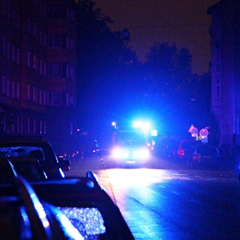 Ein Rettungswagen fährt während eines Stromausfalls mit Blaulicht durch eine dunkle Straße.