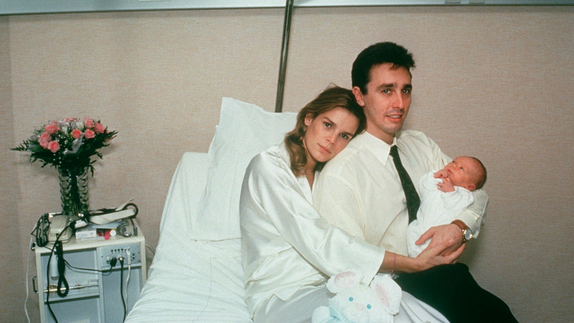 Prinzessin Stéphanie von Monaco sitzt auf einem Bett und lehnt ihren Kopf auf die Schulter ihres damaligen Ehemanns Daniel Ducruet. Der hält ihren Sohn Louis im Arm. Stéphanie umarmt beide.