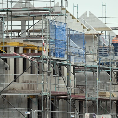 Gerüste stehen an noch nicht fertig gebauten Häusern in einem Neubaugebiet.