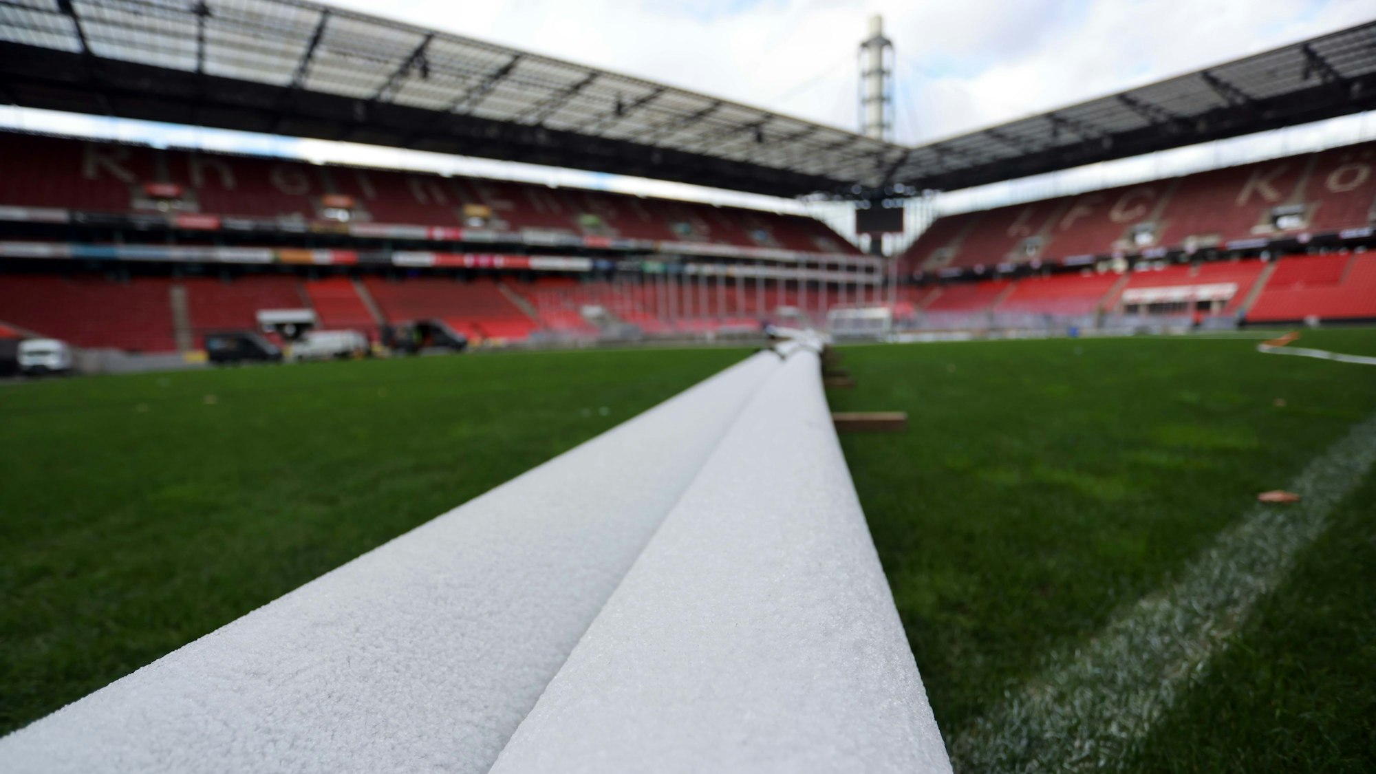 Vereiste Rohre führen quer über den Rasen des Stadions zur Eisfläche.