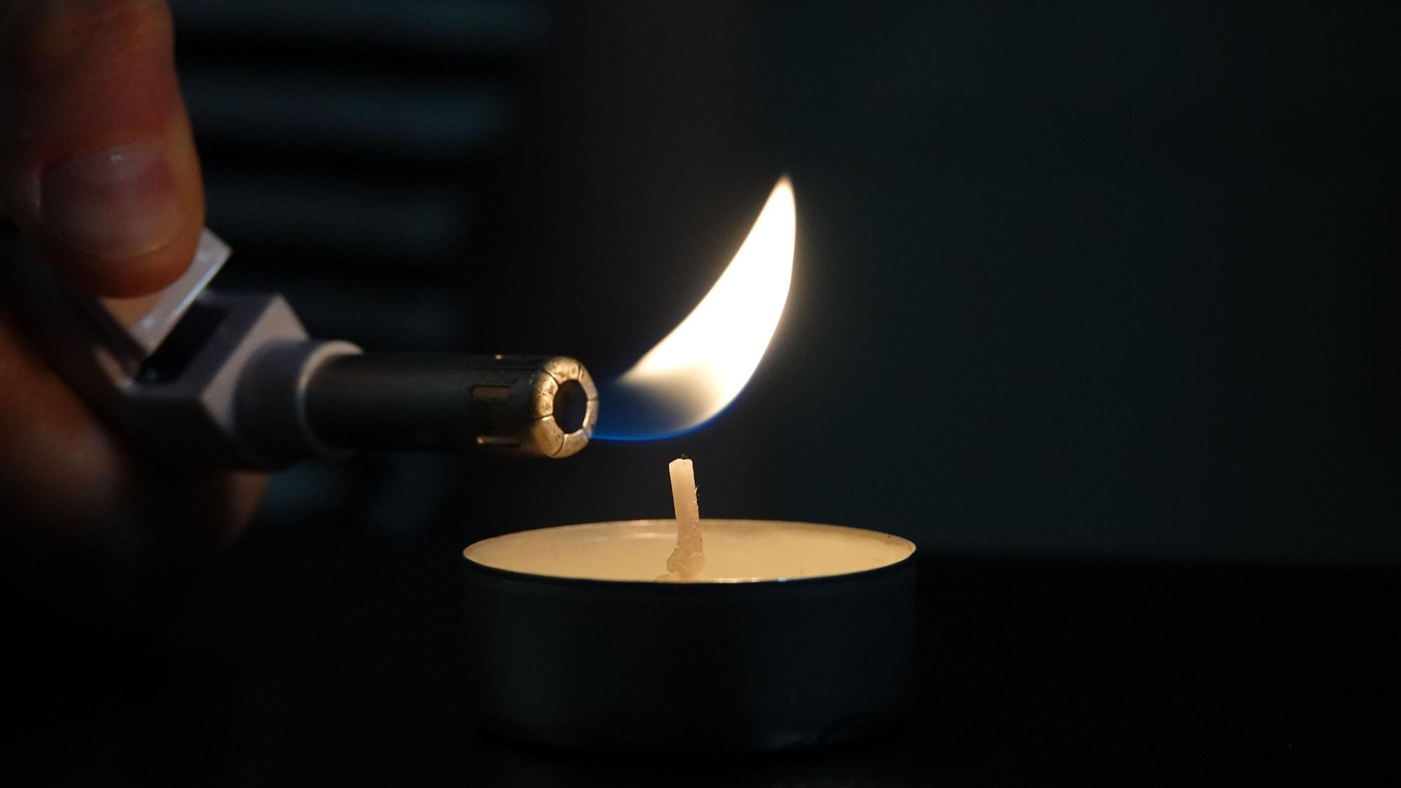 Teelicht, das mit einem Feuerzeug angezündet wird