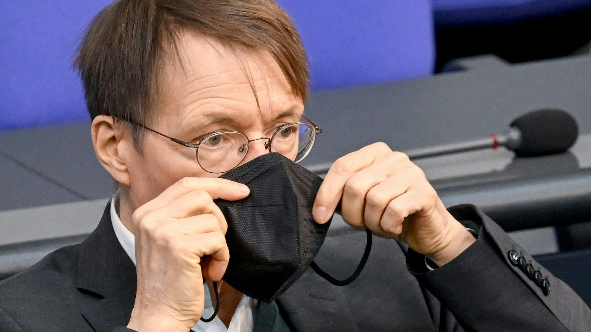 Karl Lauterbach (SPD), Bundesminister für Gesundheit, setzt seine Maske nach seiner Rede bei der Sitzung im Bundestag wieder auf.