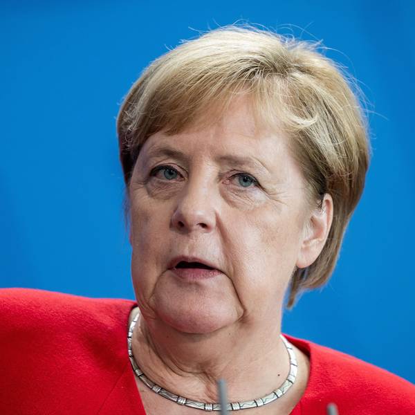Ex-Bundeskanzlerin Angela Merkel blickt bei einer Pressekonferenz ins Publikum. Die CDU-Politikerin steht vor einer blauen Wand.