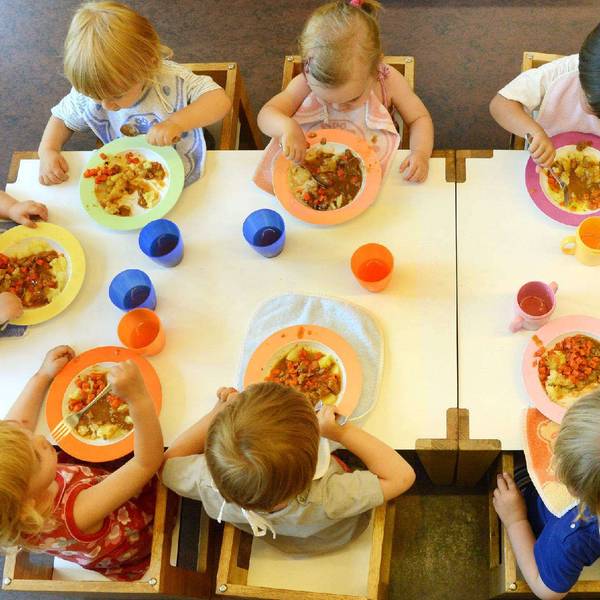 Kinder sitzen in einer Kindertageseinrichtung beim Mittagessen.