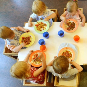 Kinder sitzen in einer Kindertageseinrichtung beim Mittagessen.