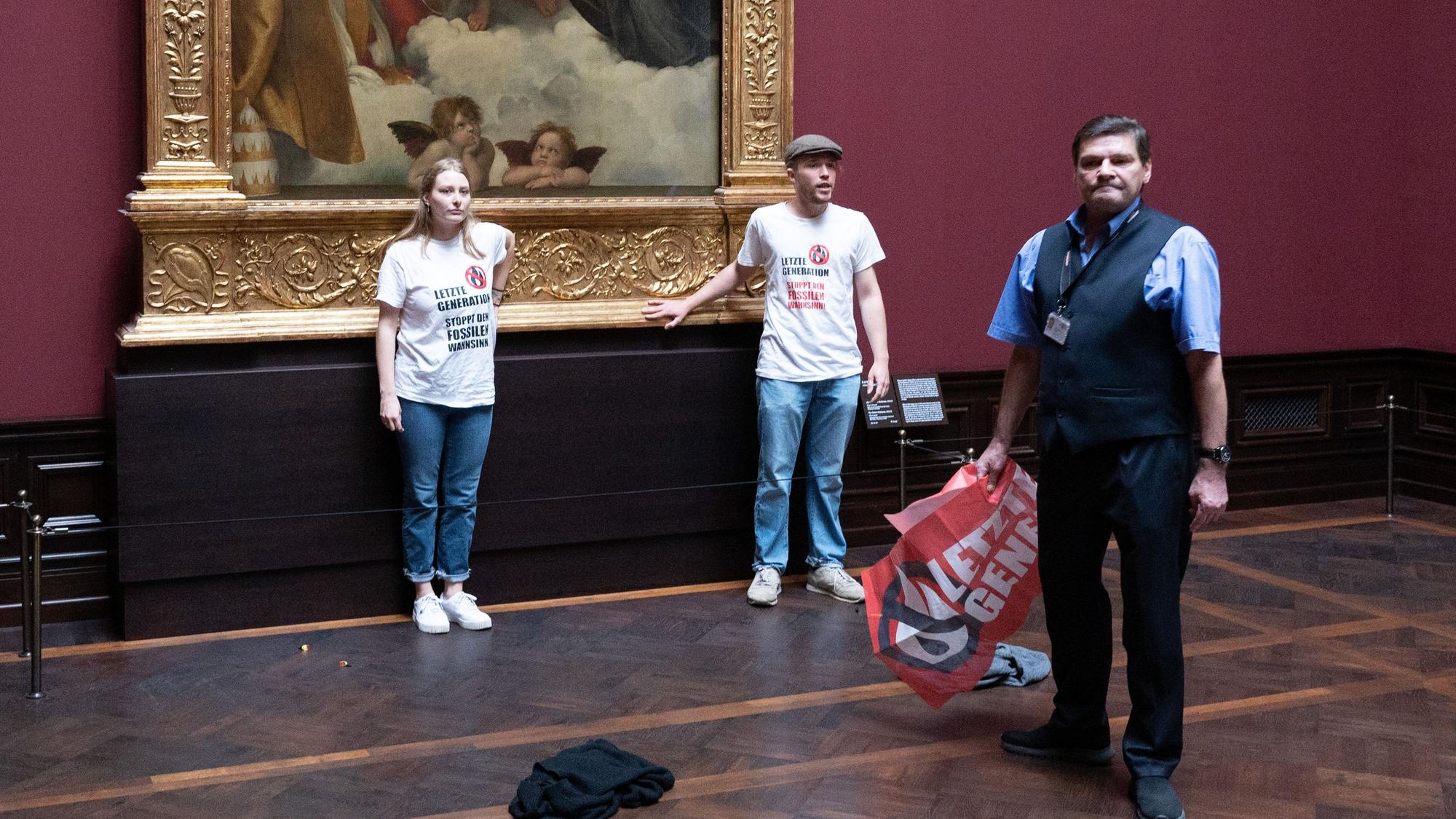 August 2022: Zwei Umweltaktivisten der Gruppe „Letzte Generation“ stehen in der Gemäldegalerie Alte Meister in Dresden an dem Gemälde „Sixtinische Madonna“ von Raffael.
