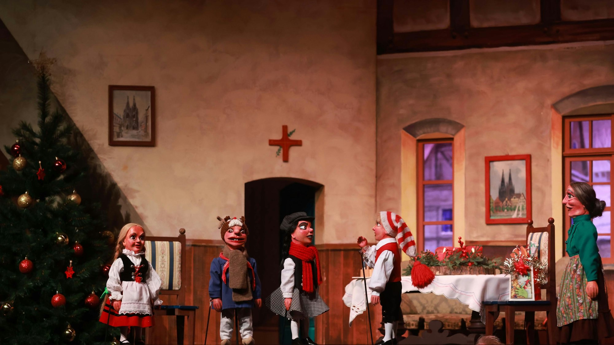 Die Figuren des Hänneschen stehen in einer weihnachtlich geschmückten Kulisse.