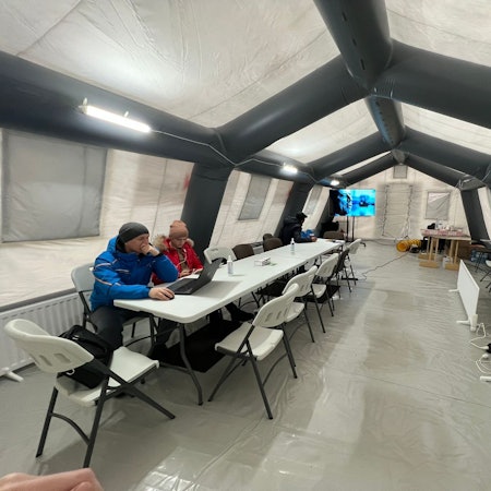 Zwei Bürger sitzen in einem beheizten Zelt in Butscha. Nur dort gibt es nach den russischen Angriffen Strom und Internet.