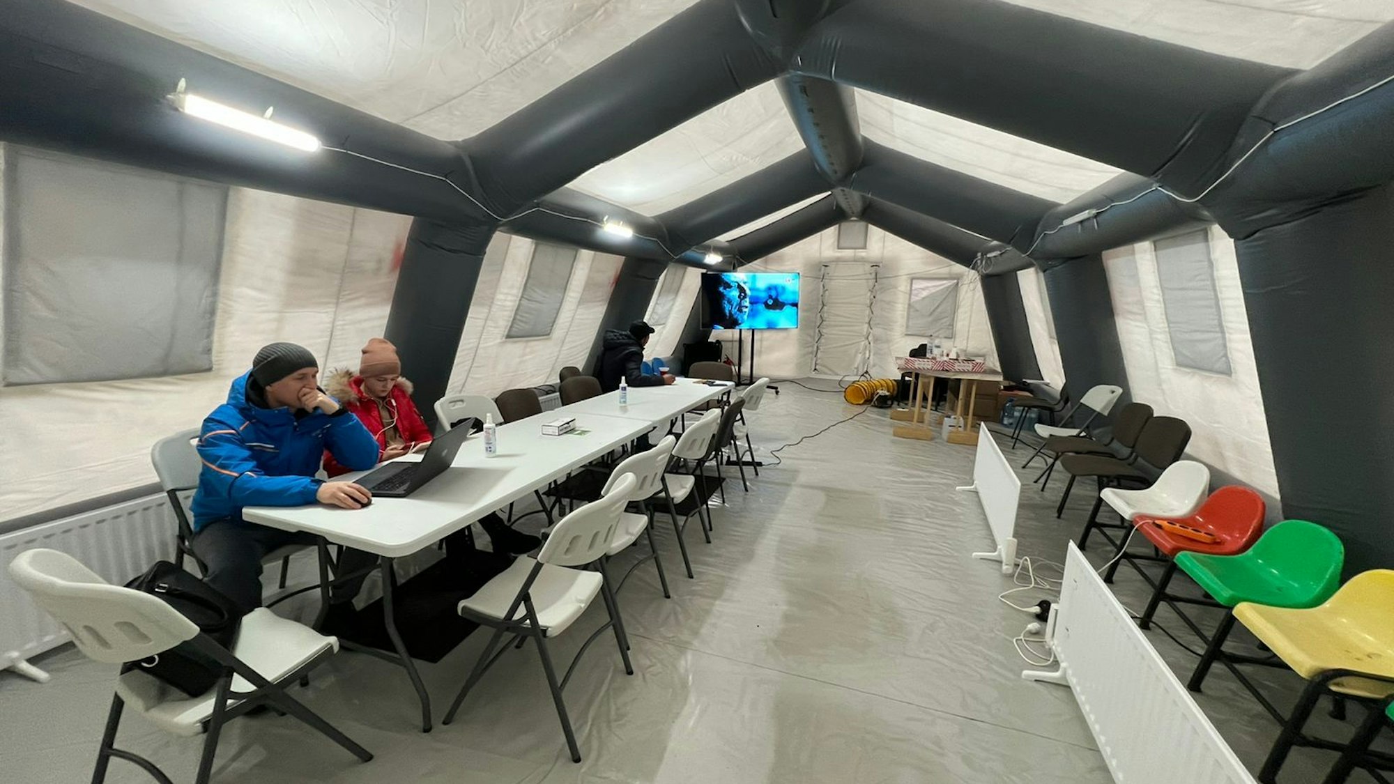 Zwei Bürger sitzen in einem beheizten Zelt in Butscha. Nur dort gibt es nach den russischen Angriffen Strom und Internet.