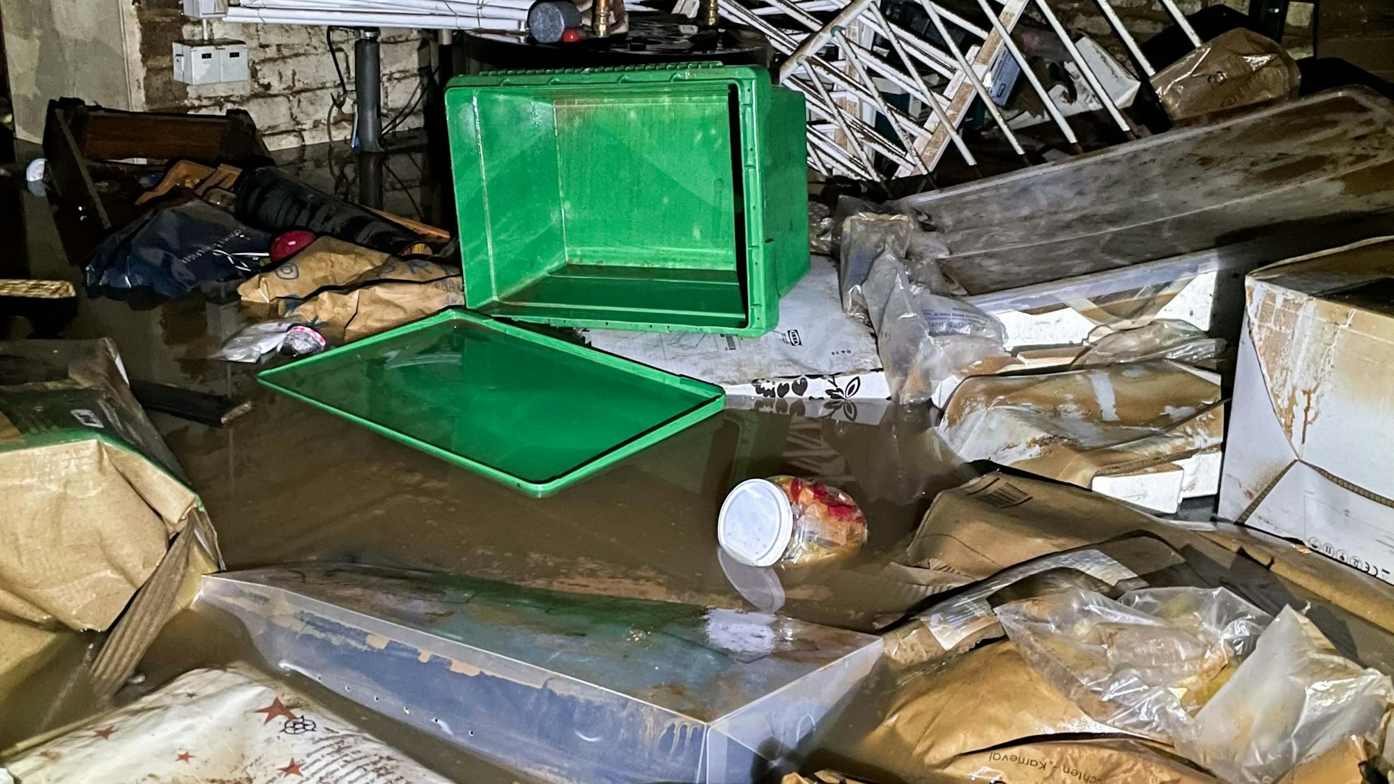 Das Symbolfoto zeigt einen bei der Hochwasserkatastrophe überfluteten Keller, in dem Gerümpel schwimmt. Im Hintergrund ist eine zerstörte Heizungsanlage zu sehen.
