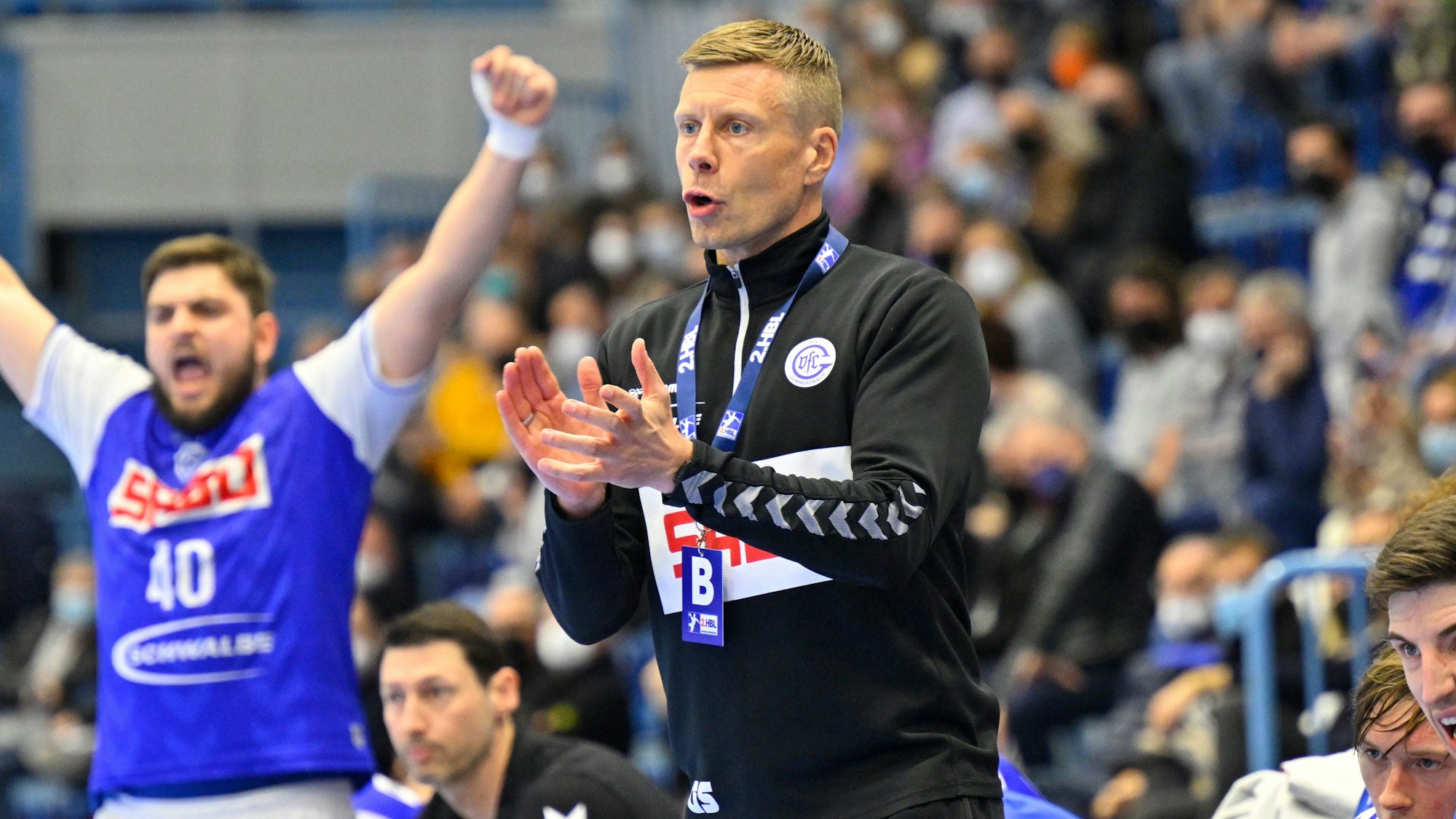 VfL-Trainer Gudjon Valur Sigurdsson steht am Rand des Handballfeldes und gestikuliert mit den Händen. Im Hintergrund jubelt VfL-Kreisläufer Jonas Stüber.