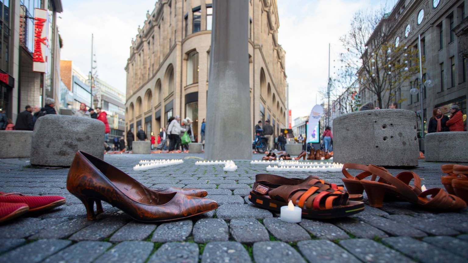 Schuhe von Frauen stehen auf der Kölner Schildergasse, umringt von Teelichten.