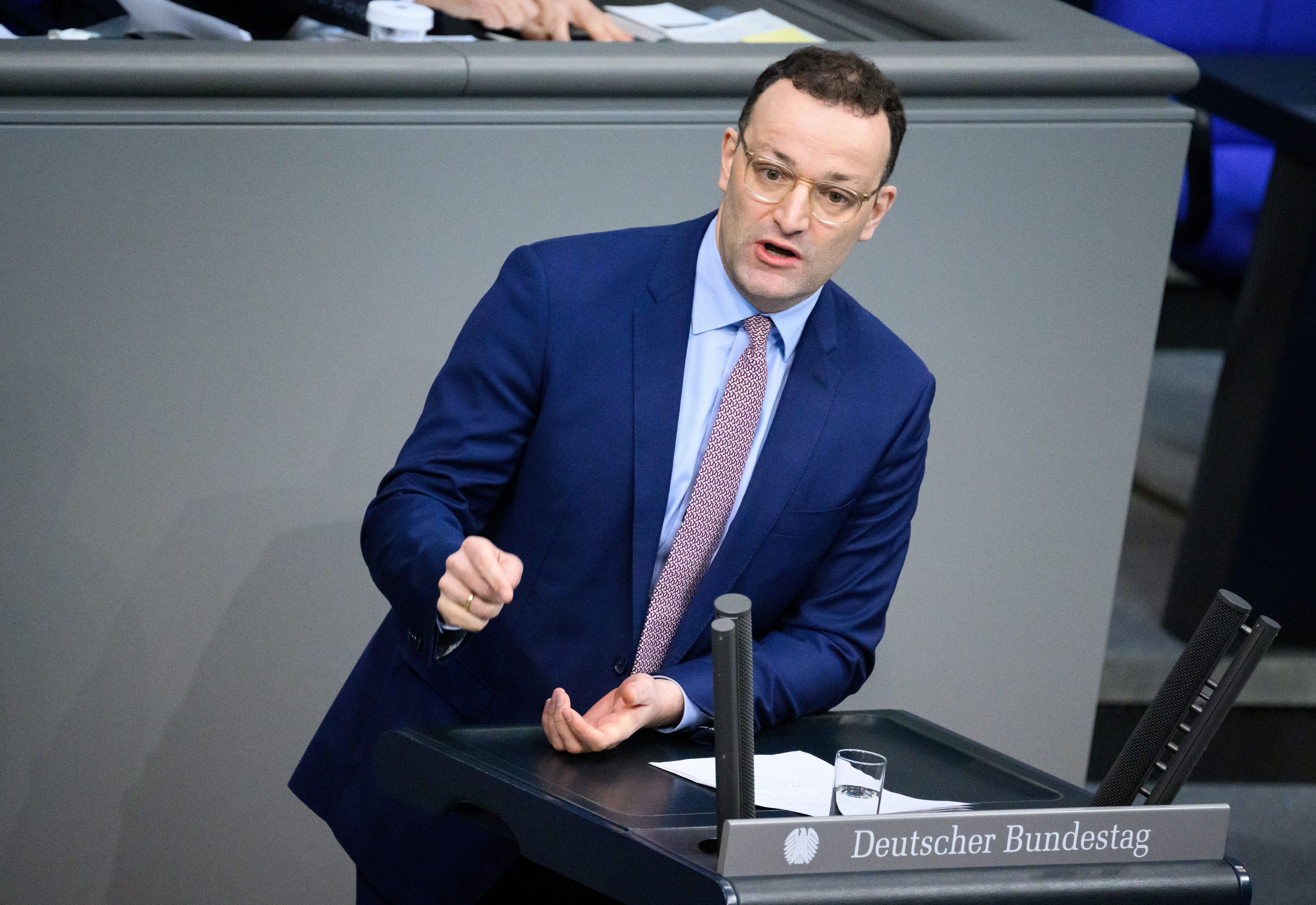 Jens Spahn (CDU) steht hinter einem Pult und spricht im Deutschen Bundestag in ein Mikrofon.