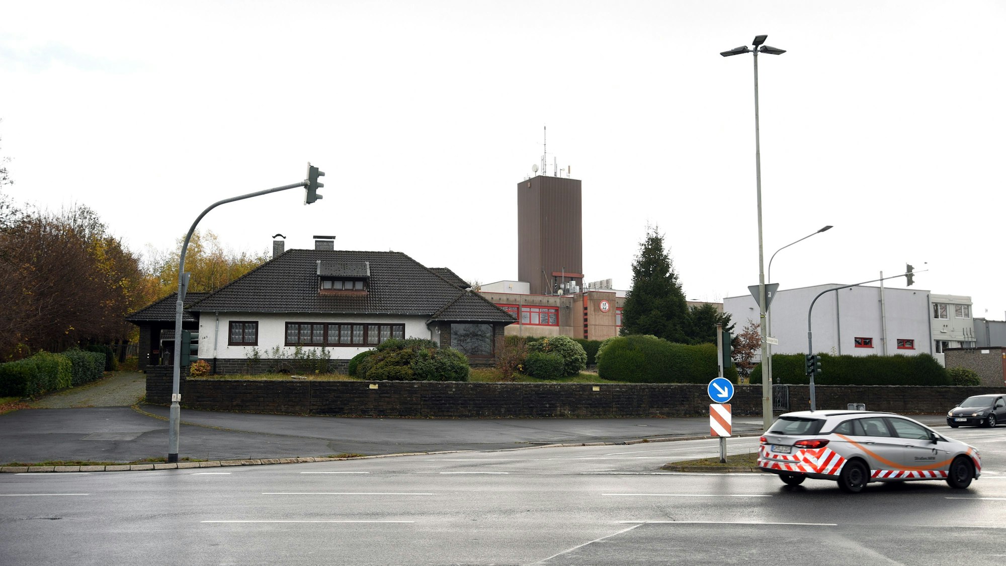 Blick auf eine Ampelkreuzung, im Hintergrund ein Wohnhaus und dahinter das Brandschutzzentrum in Marienheide-Kotthausen