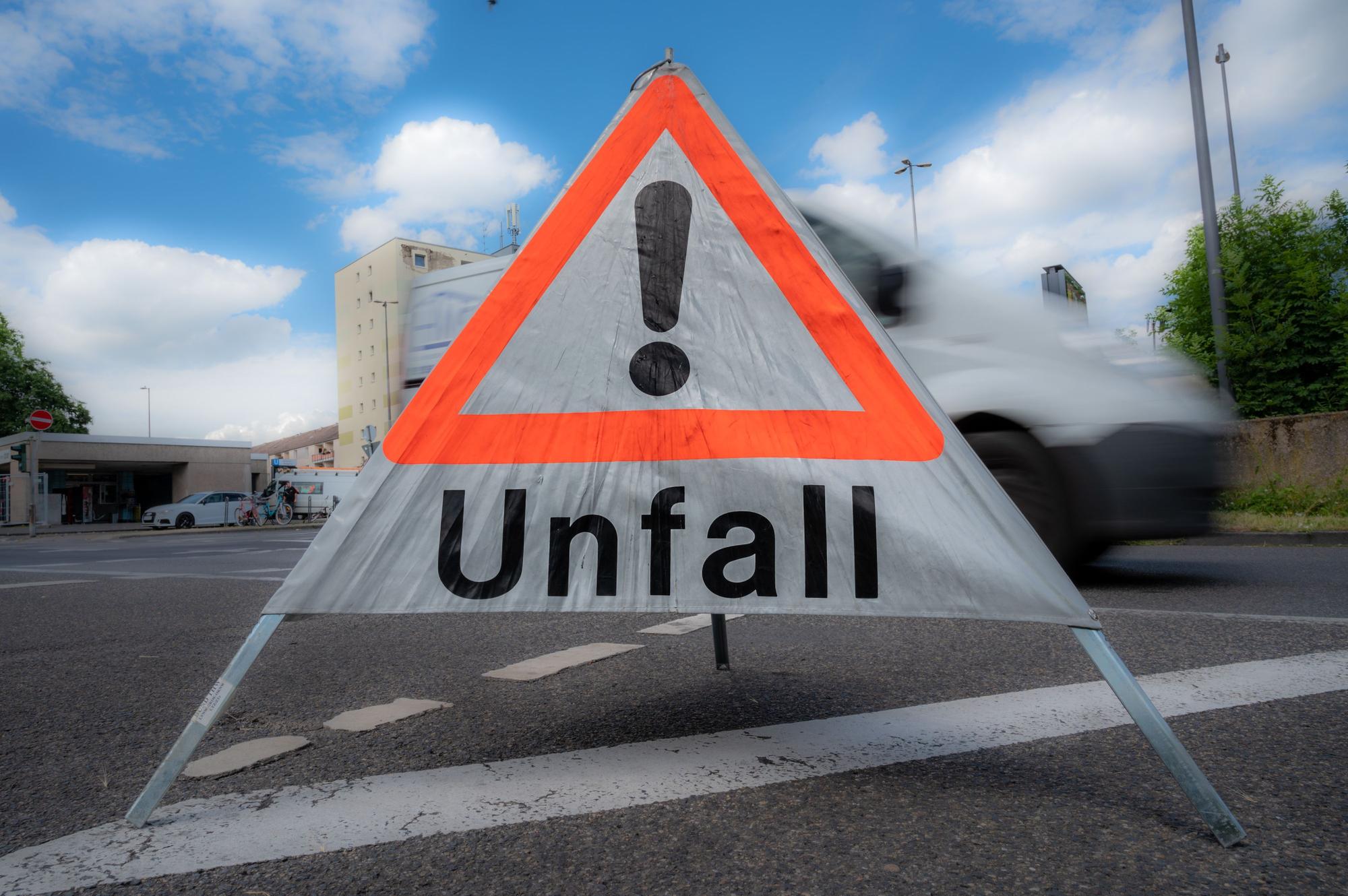 Das Symbolbild zeigt ein mobiles Schild, ähnlich eines Warndreiecks, mit der Aufschrift Unfall