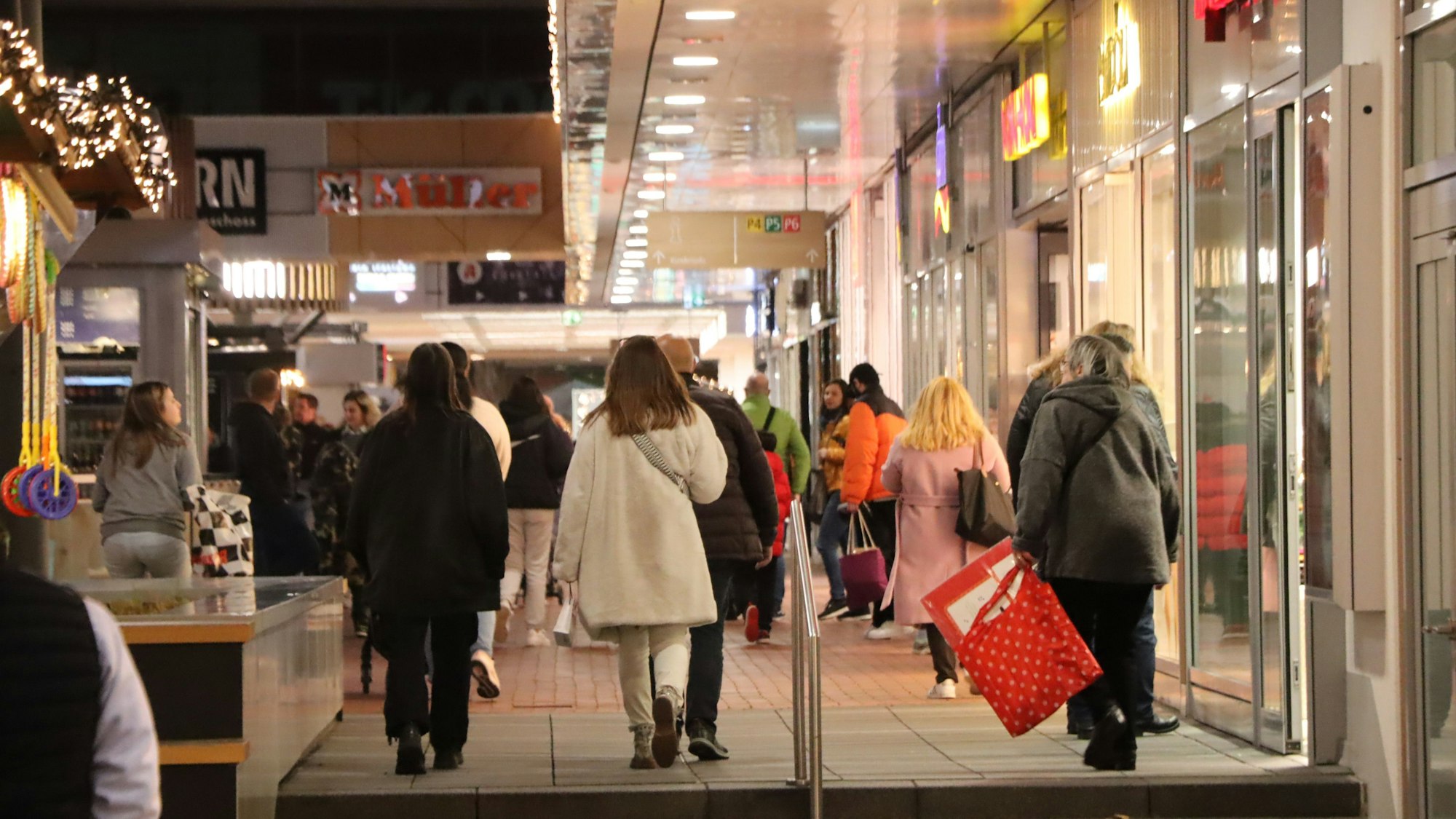 Einkäuferinnen und Einkäufer laufen durch den Hürth Park.