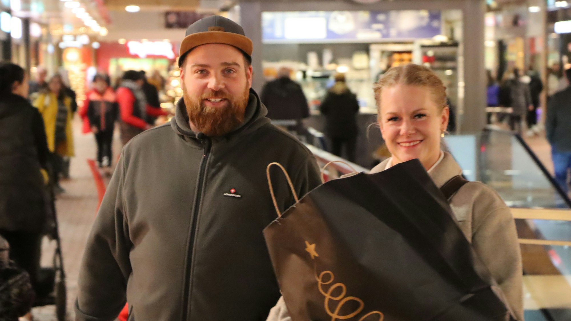 Ein junges Pärchen hält seine Einkaufstasche in die Kamera.