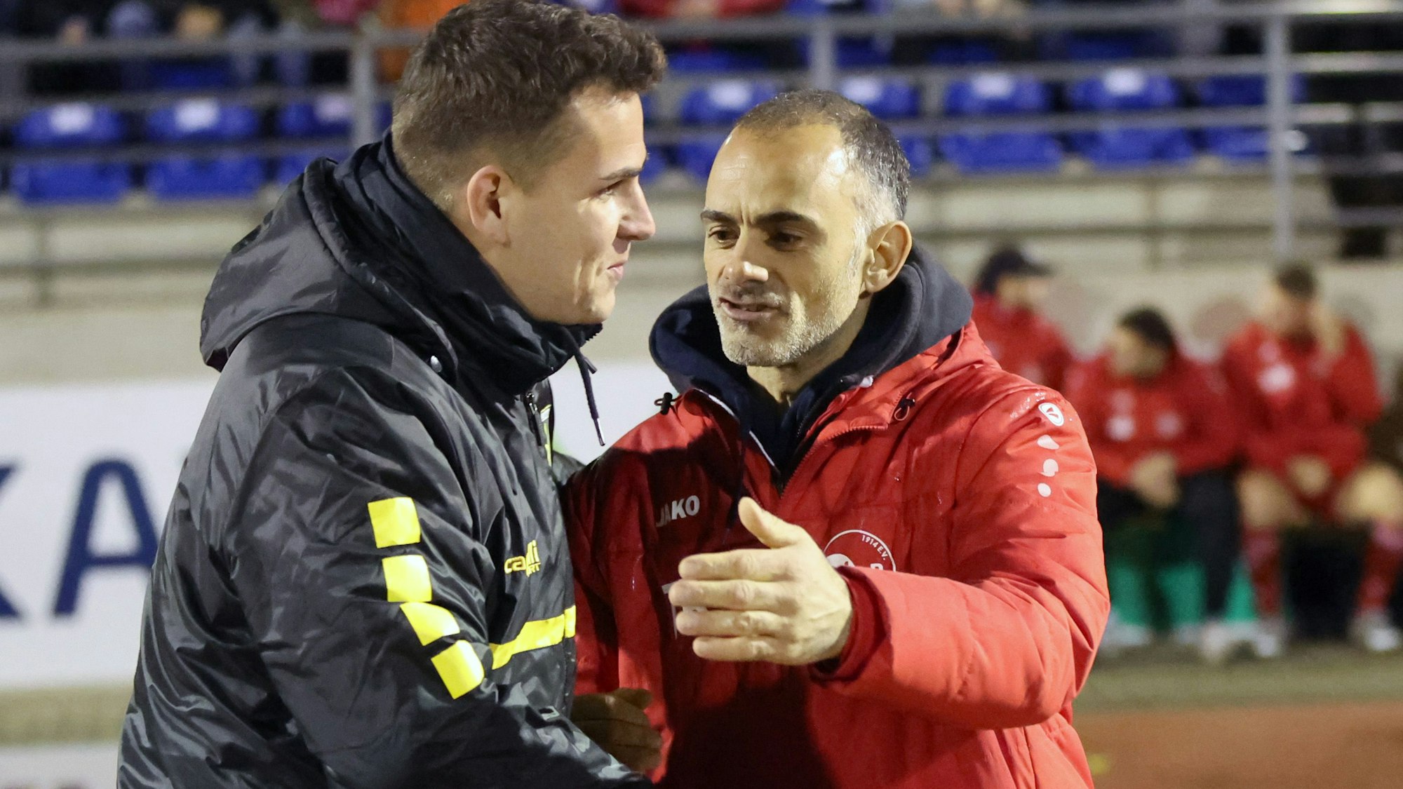 Neben dem Spielfeld begrüßen sich die beiden Trainer vor dem Anpfiff. Links ist Aachens Trainer Helge Hohl zu sehen und rechts VfR-Co-Trainer Andrea Esposito. Beide geben sich die Hand.
