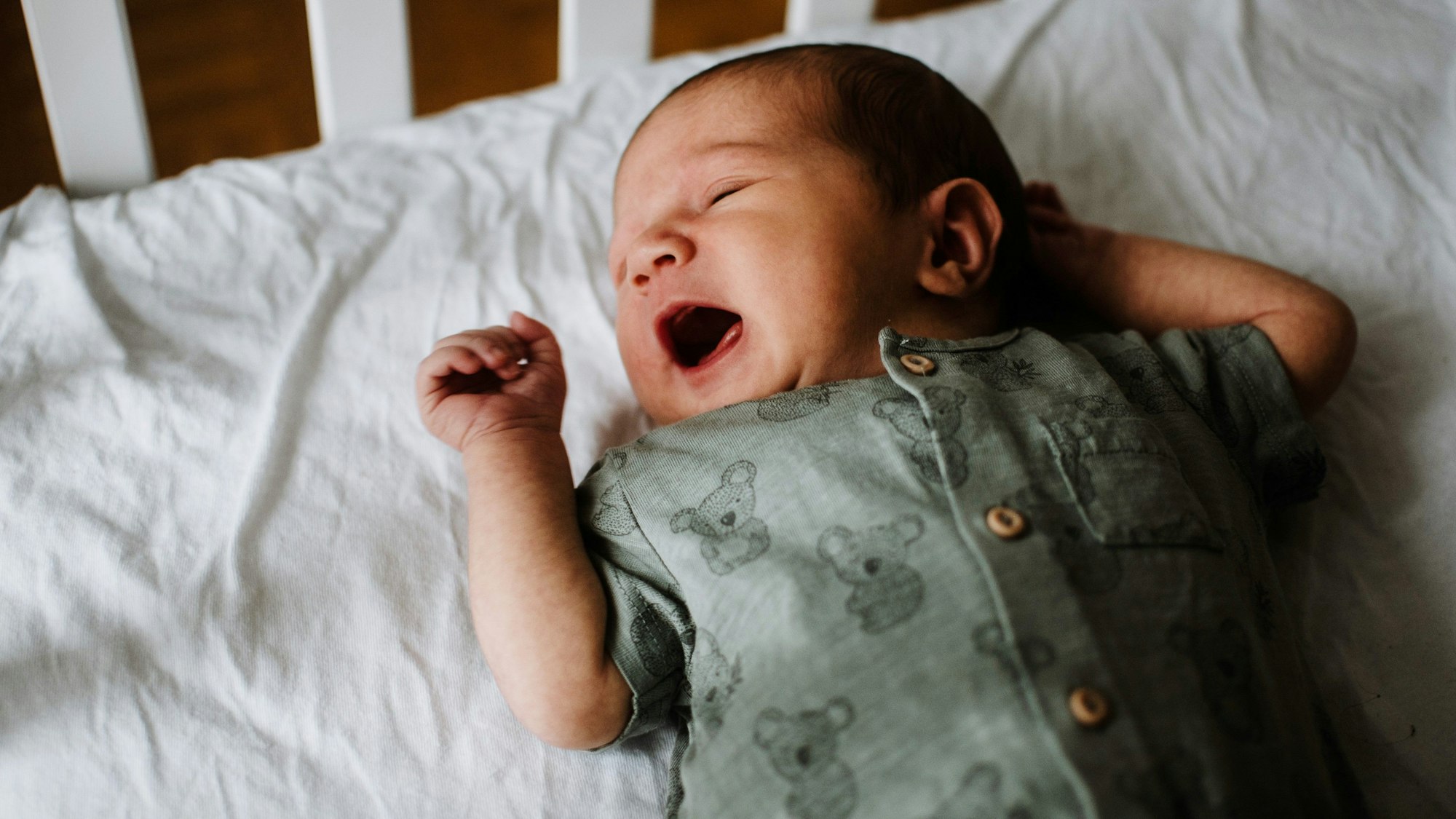 Ein Baby liegt im Bett und schreit.