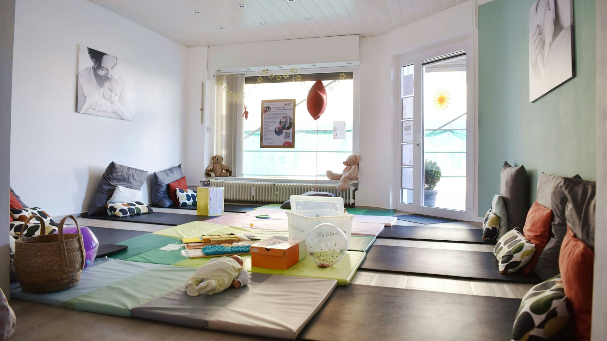 Der Kursraum in Henrys Eltern-Kind-Kompetenzzentrum Weilerwist ist hell und gemütlich eingerichtet. Er bietet viele Kissen und Matten zum entspannten Liegen.