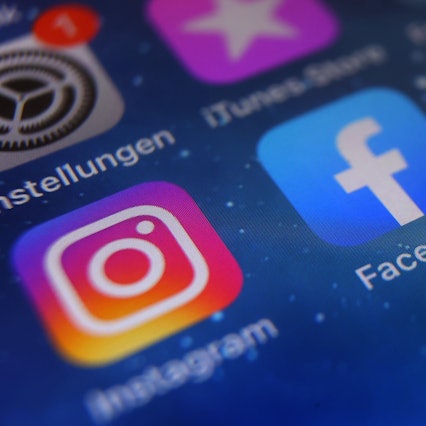 Auf dem Bildschirm eines Smartphones sind die Icons von Instagram, Facebook und WhatsApp zu sehen.