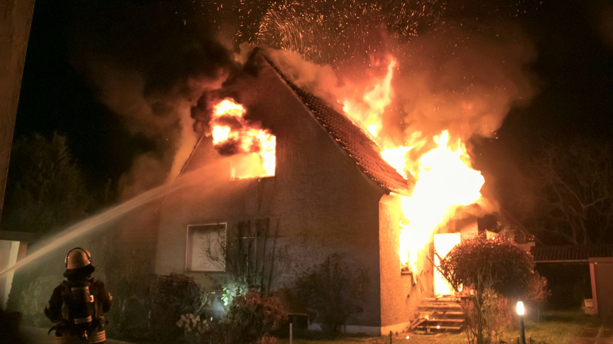 26.11.2022, Nordrhein-Westfalen, Lübbecke: Feuerwehrleute bekämpfen am frühen Morgen einen Brand in einem Einfamilienhaus. Das Gebäude sei in der Nacht auf Samstag komplett zerstört worden, sagte ein Sprecher der Polizei.