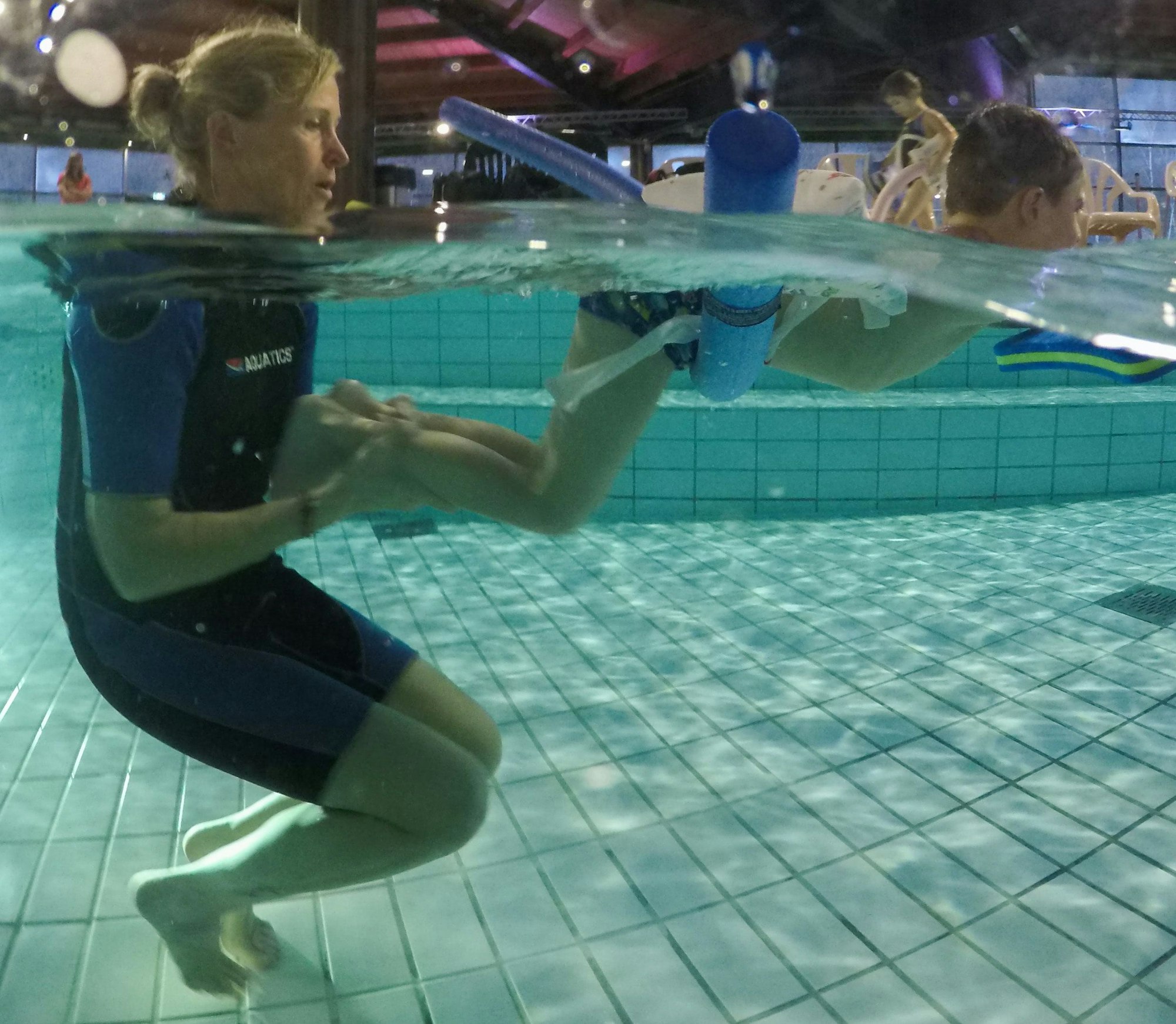 Eine Schwimmlehrerin hilft einem Kind, sich im Wasser fortzubewegen.
