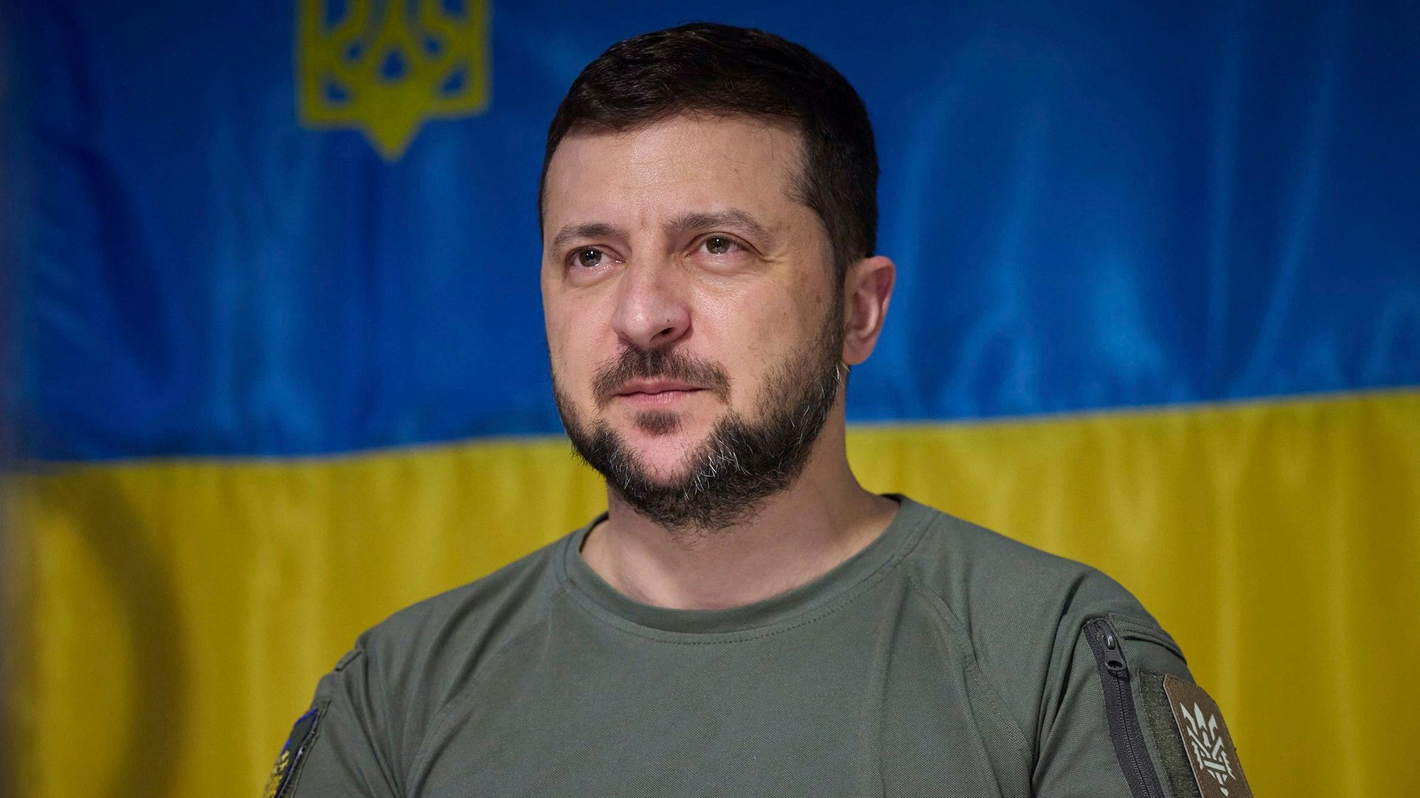 Der ukrainische Präsident Wolodymyr Selenskyj steht vor einer ukrainischen Flagge und bereitet sich auf eine Rede vor.