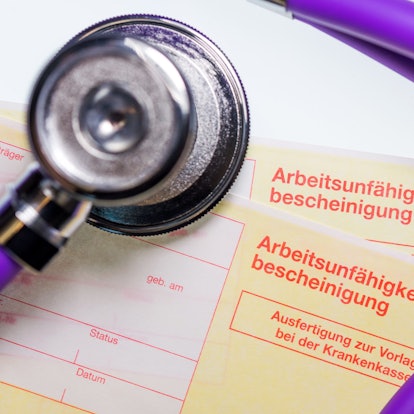 Eine Arbeitsunfähigkeitsbescheinigung und ein Stethoskop liegen auf einem Tisch.