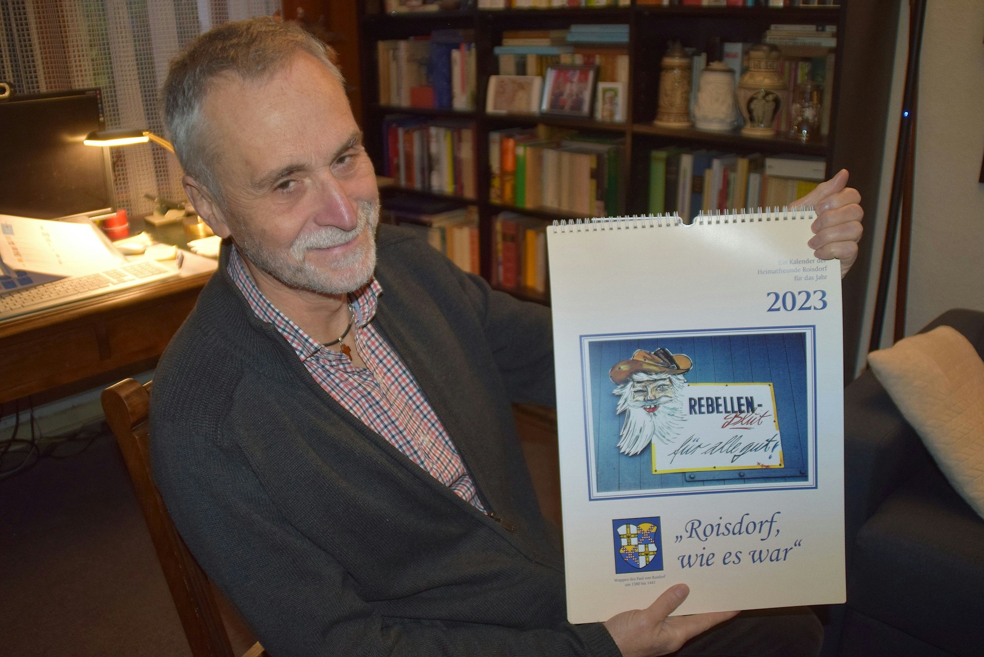 18. November 2022: Bornheim-Roisdorf. Der Vorsitzende der Heimatfeunde Roisdorf Ernst Gierlich präsentiert den Heimatkalender 2023 mit dem "augenzwinkernden Rebell".