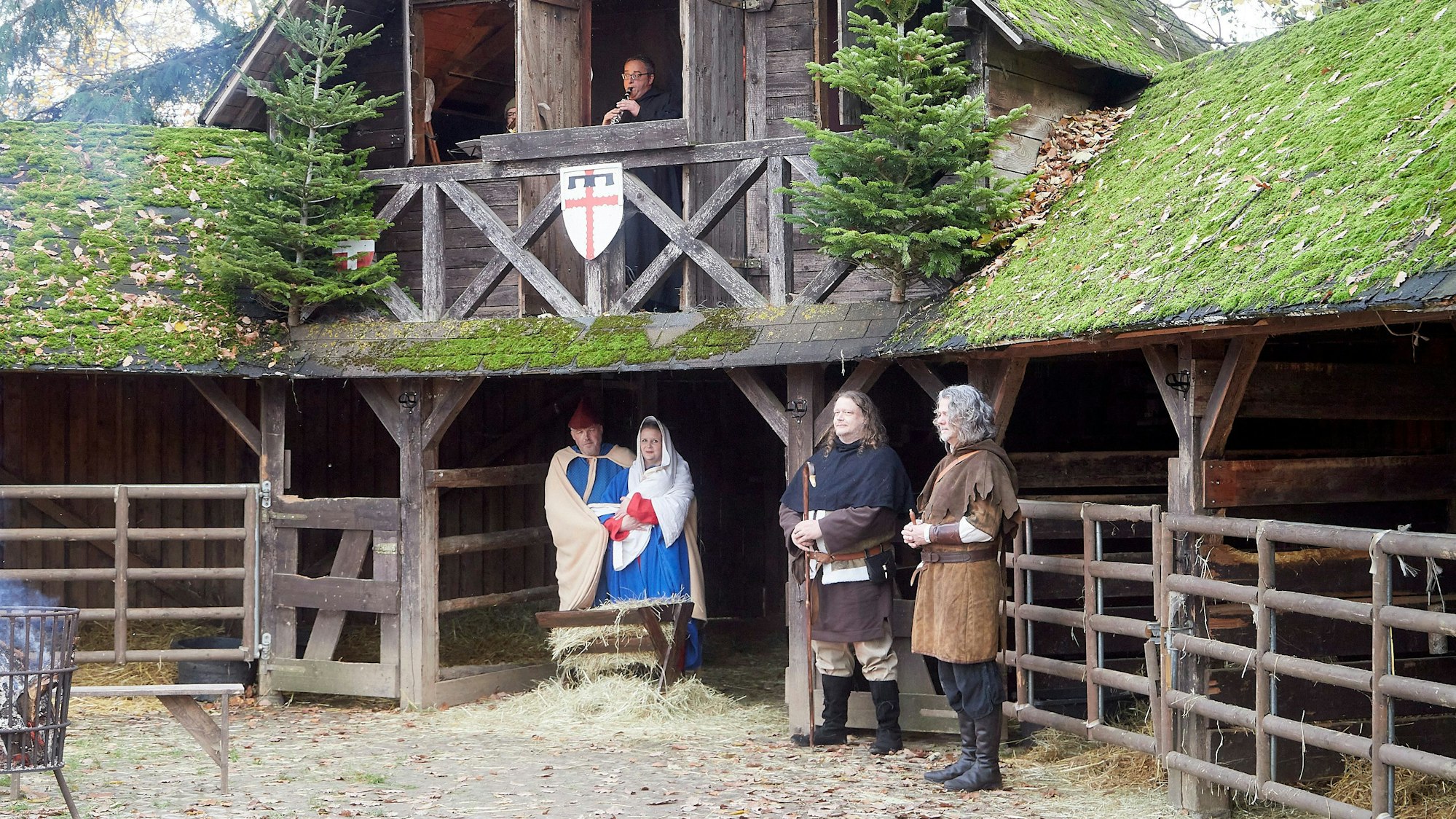 Krippenspiel auf Burg Satzvey. Maria und Josef warten im Stall. Über ihnen erzählt aus einem Fenster ein Mann die Weihnachtsgeschichte.