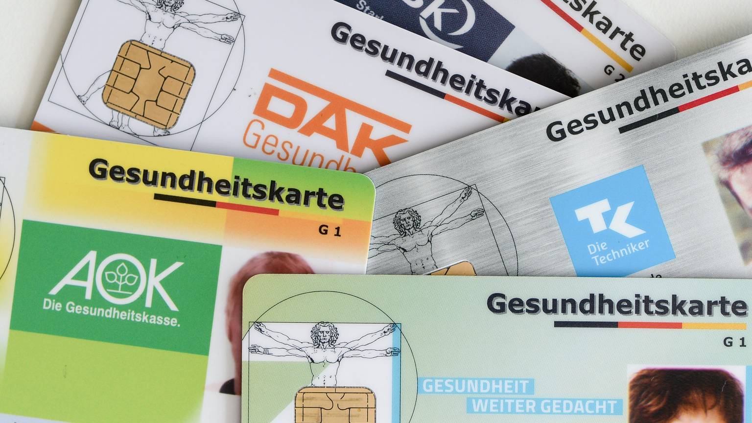 Gesundheitskarten verschiedener Krankenkassen liegen auf einem Tisch.