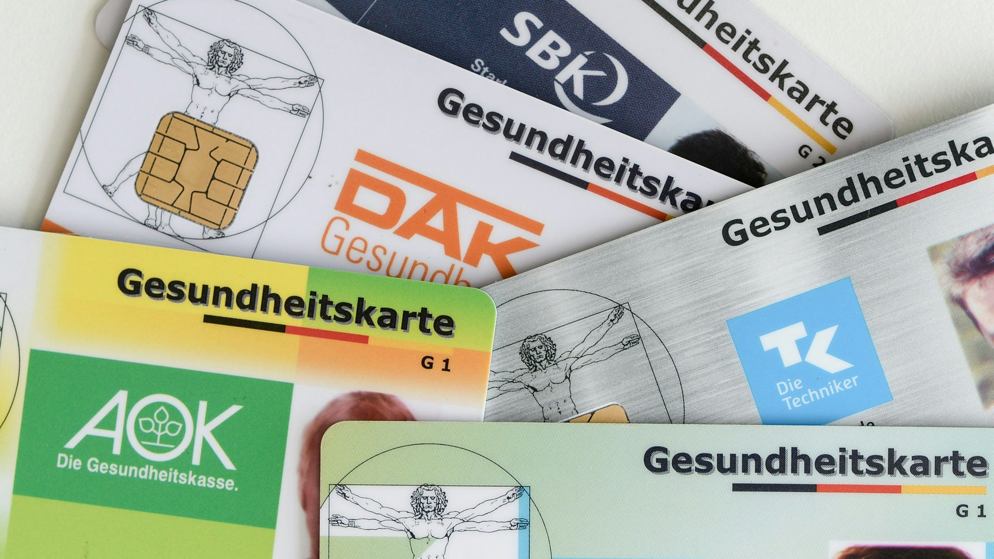 Gesundheitskarten verschiedener Krankenkassen liegen auf einem Tisch.