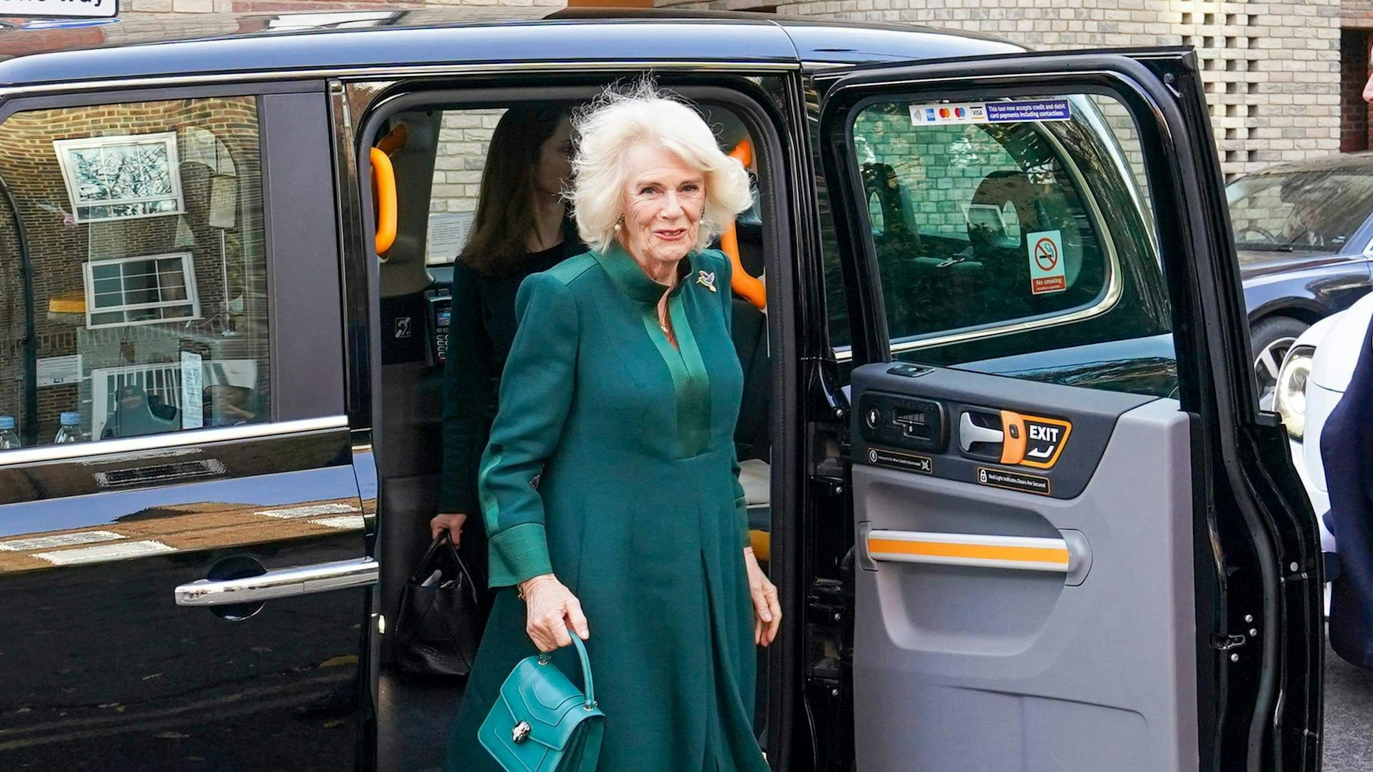 In einem grünen Dress steigt Königin Camilla steigt aus einem Londoner Taxi.