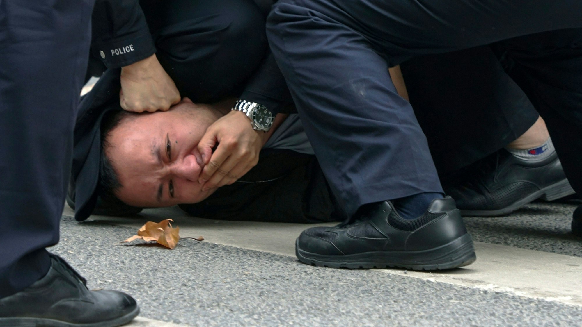 Polizisten halten am Sonntag einen Demonstranten während einer Demonstration auf einer Straße in Shanghai fest.