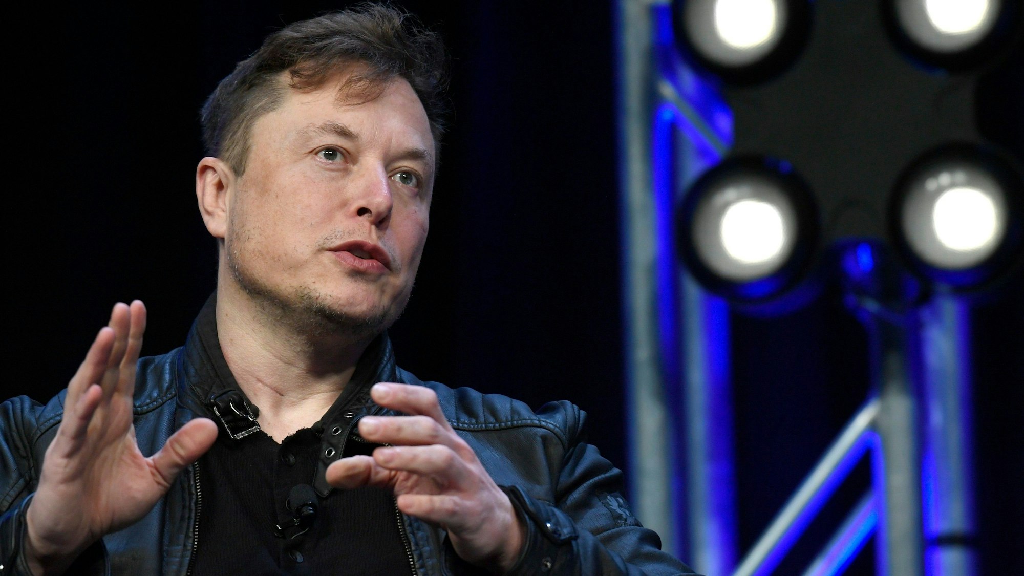 Elon Musk spricht auf einer Konferenz, er gestikuliert mit den Händen.