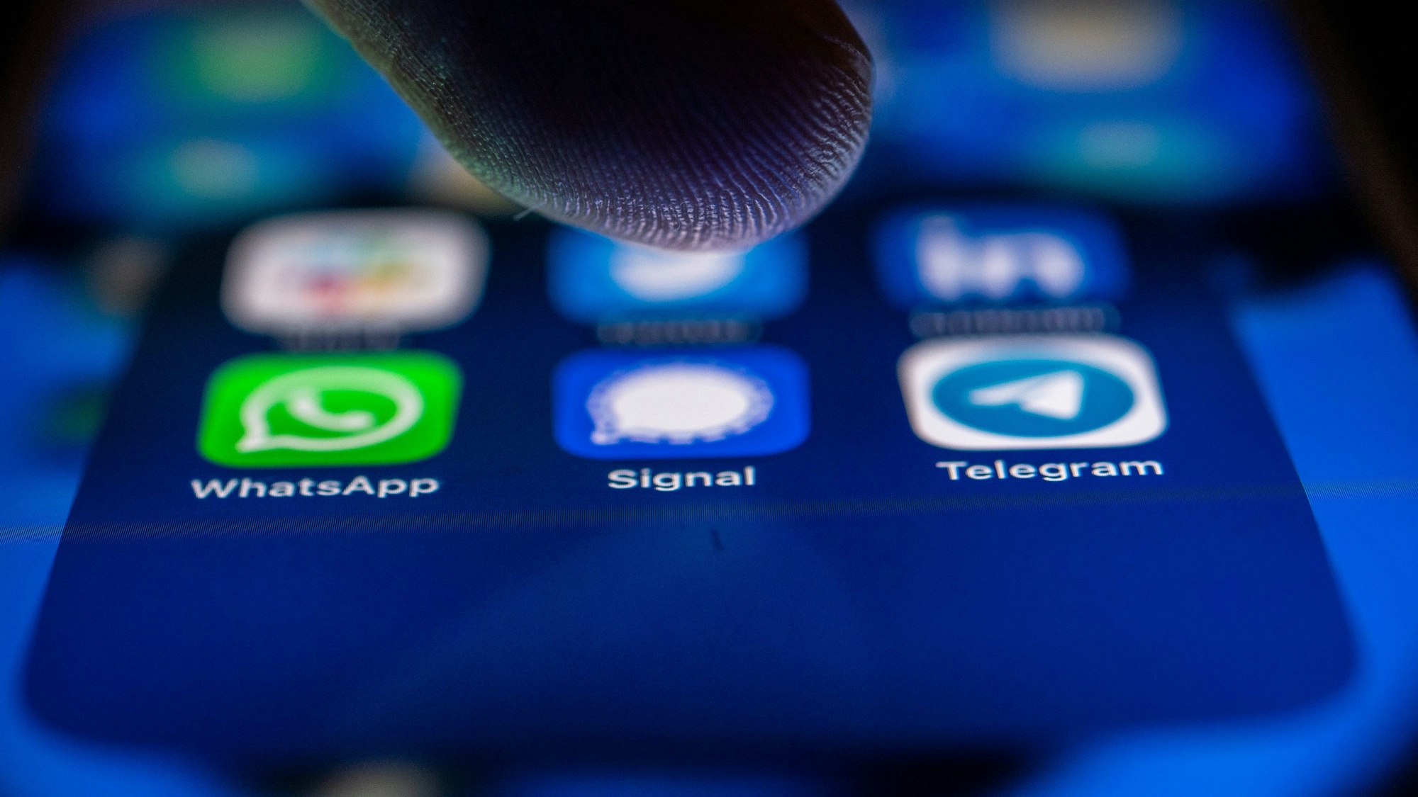 Ein Finger tippt auf einen erleuchteten Handybildschirm.