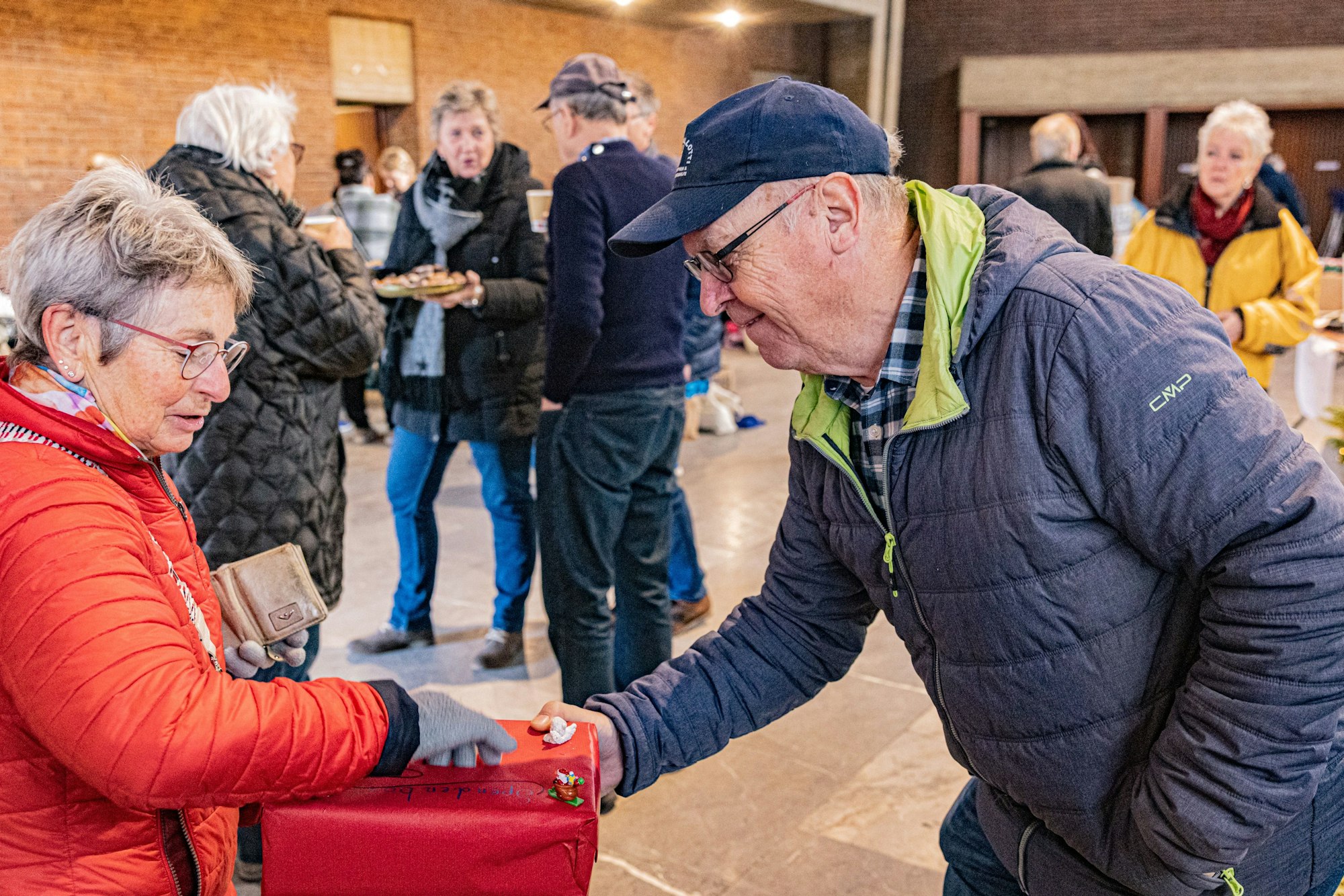 Organisator Alfred Eich nimmt in einem dekorierten Gefäß die Geldspende einer Frau an