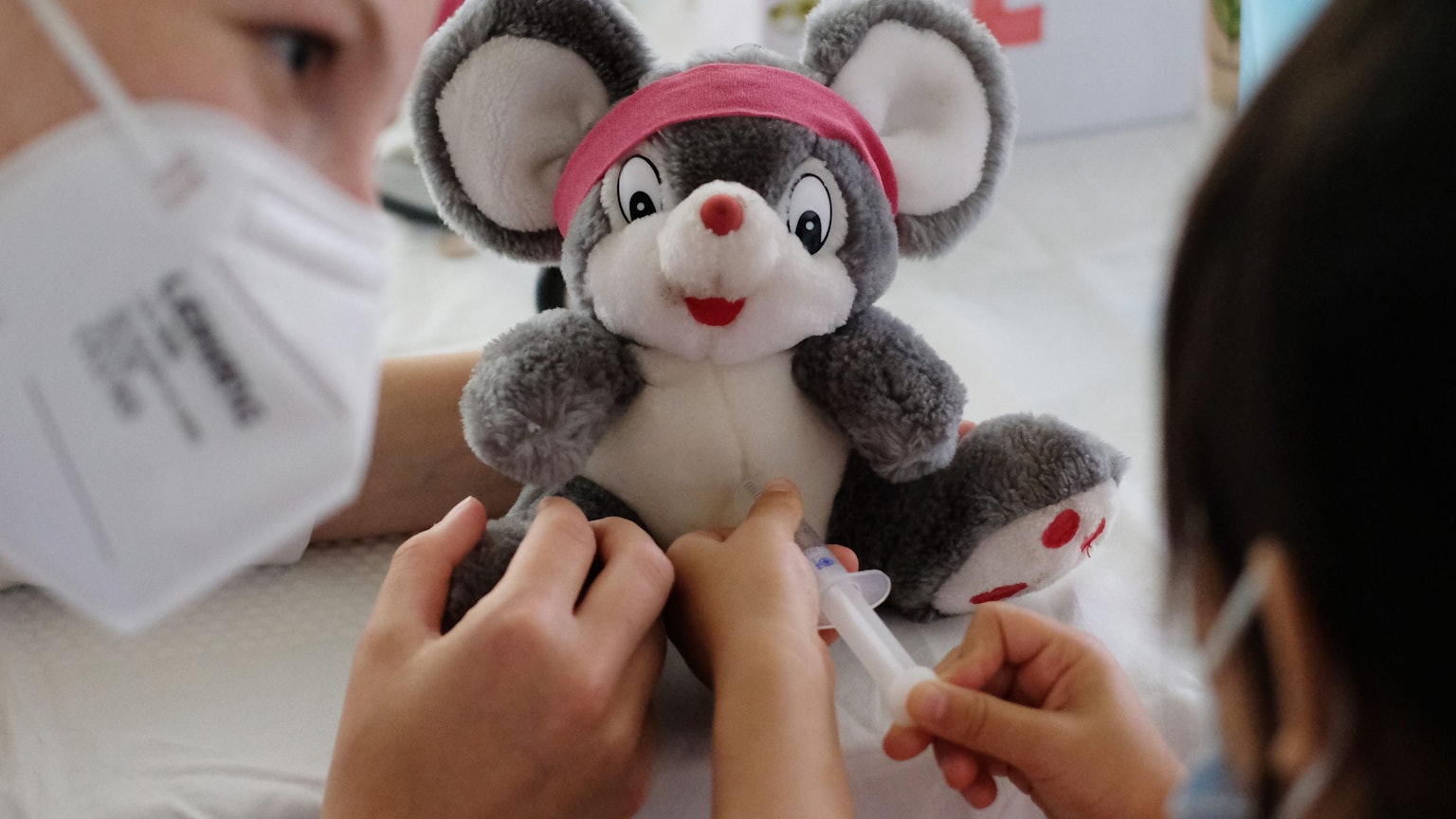 Eine Ärztin übt zusammen mit einer kleinen Patienten, wie man eine Spritze setzt. (Symbolbild)