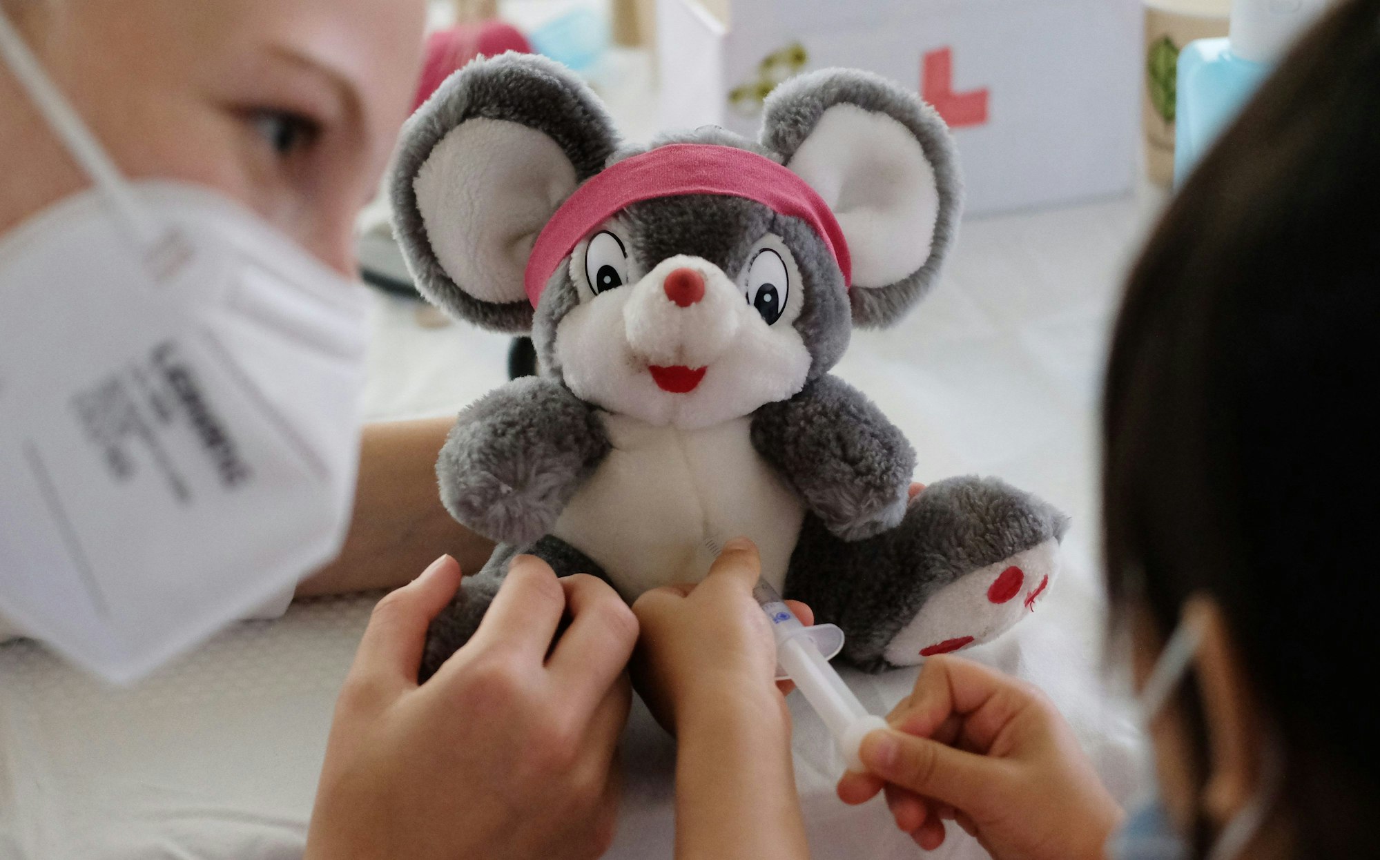 Eine Ärztin übt zusammen mit einer kleinen Patienten, wie man eine Spritze setzt. (Symbolbild)