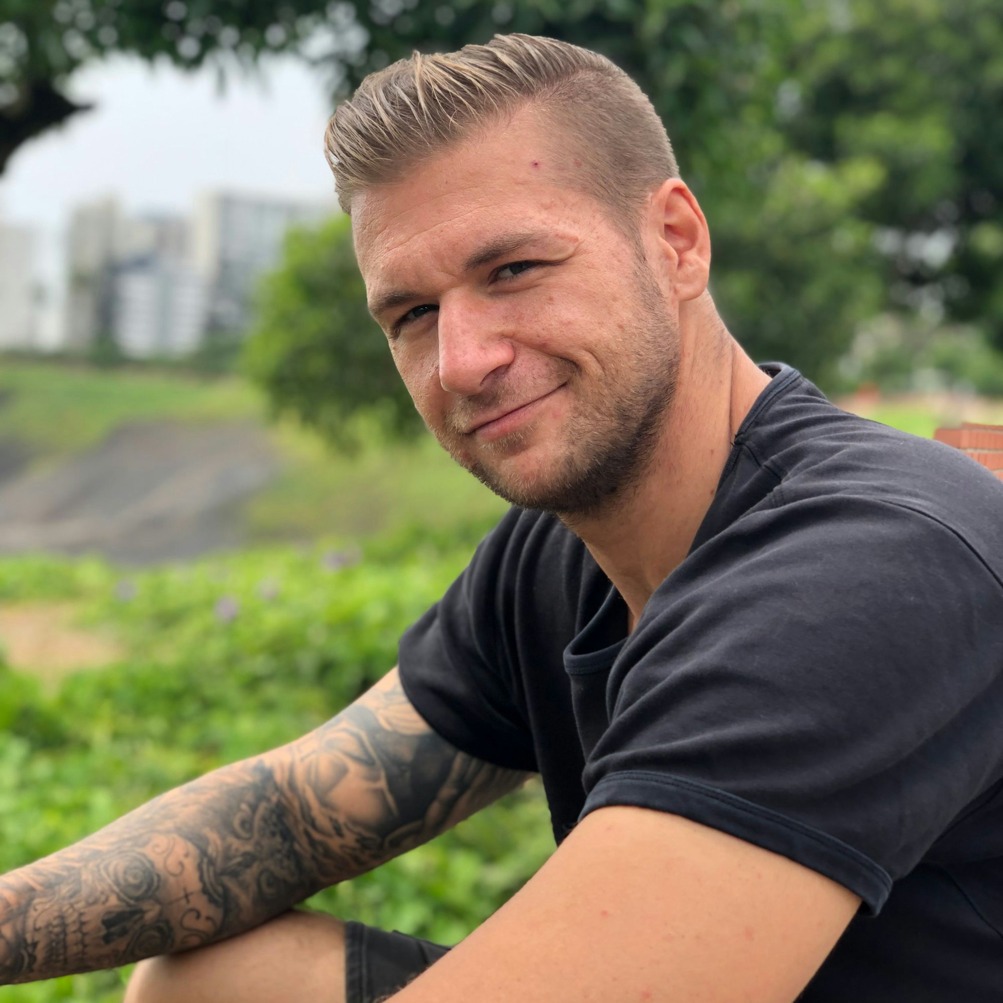 Fabian Esser trägt ein schwarzes T-Shirt. An seinem rechten Arm sind Tattoos zu sehen.