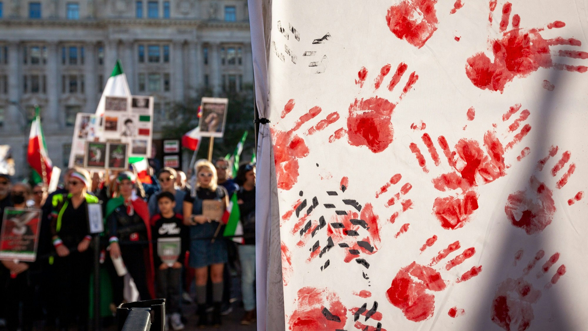 Handabdrücke aus Kunstblut zieren einen Teil der Bühne bei einer Kundgebung zur Unterstützung von Demonstranten im Iran.
