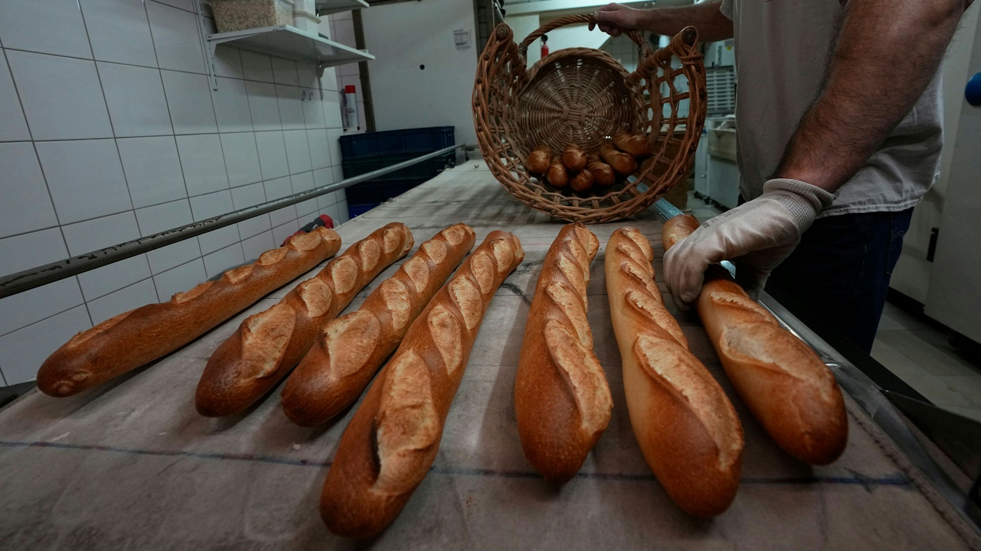 Bäcker David Buelens legt Baguettes in einer Bäckerei in Versailles, westlich von Paris, in einen Korb.